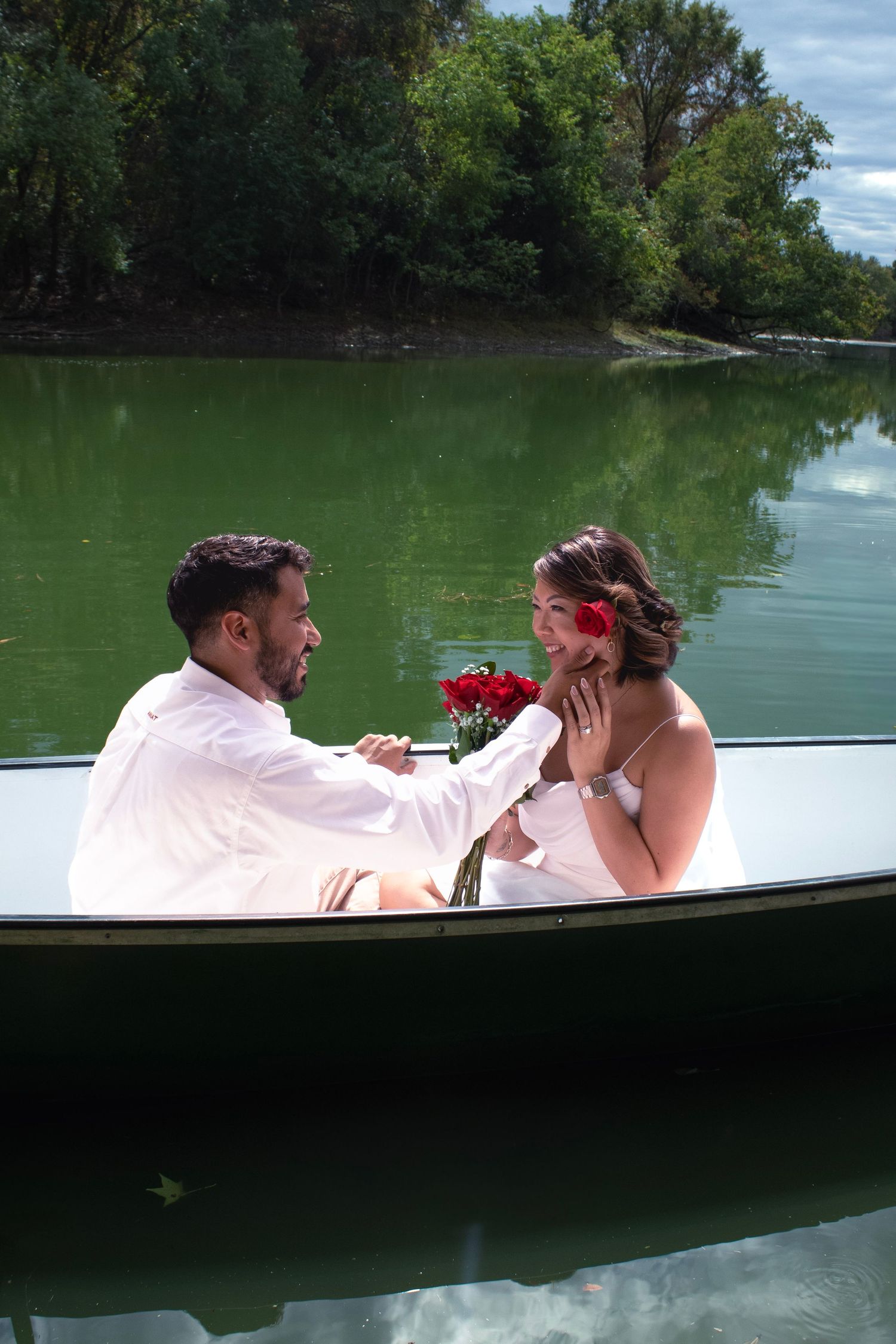 A romantic boat scene with a couple and red roses on a peaceful lake.
