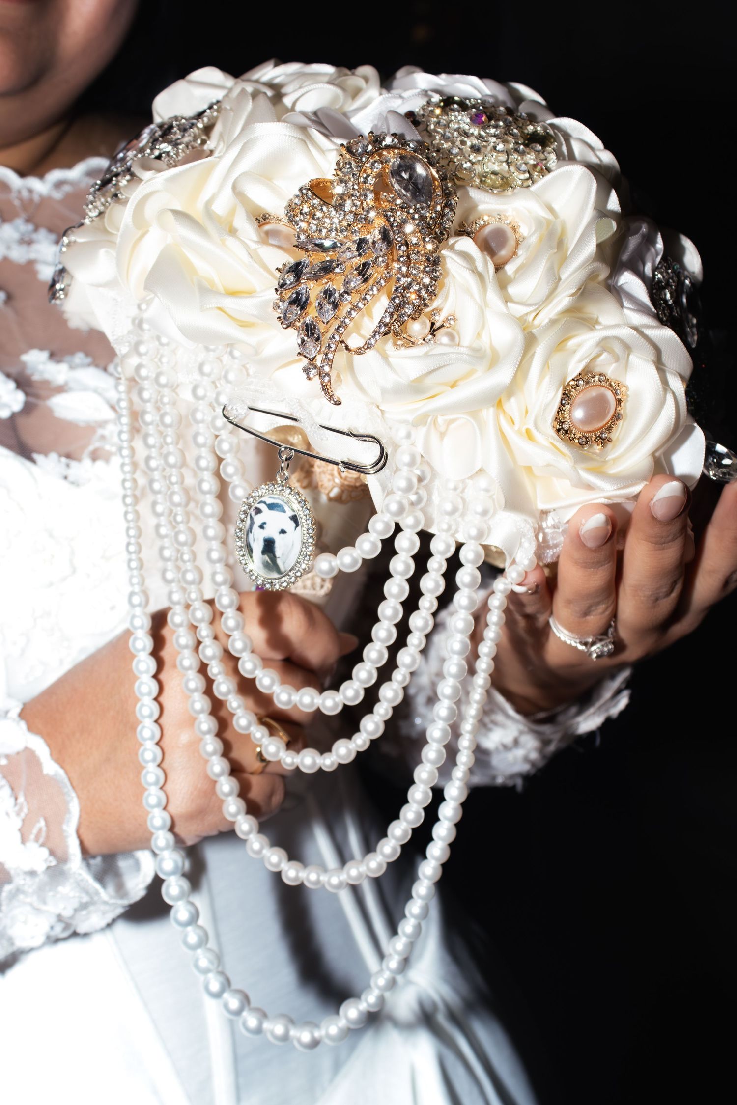 Elegant bridal bouquet decorated with pearls and crystals against dark background.