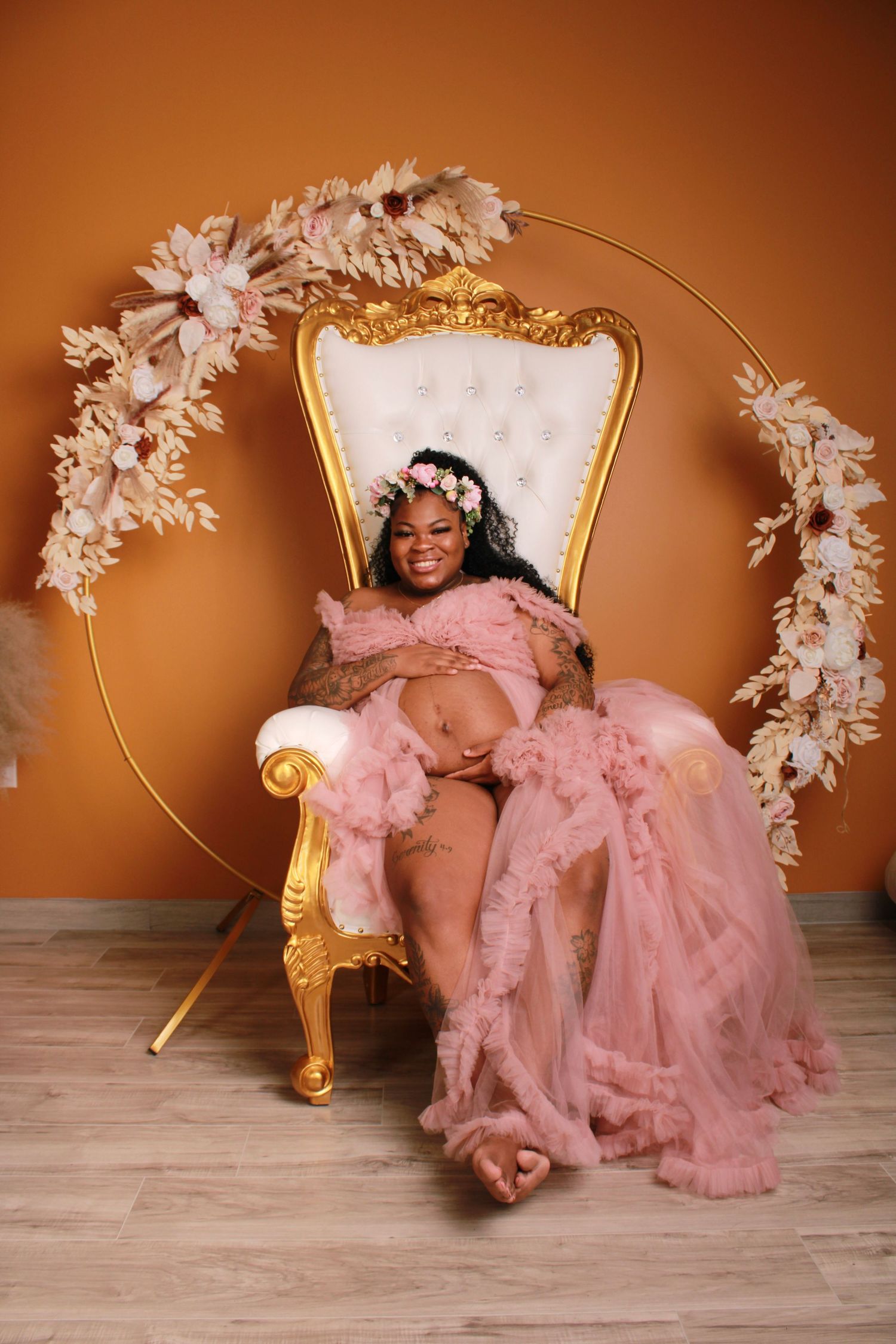 Artistic maternity session with gold chair and white floral decorations.