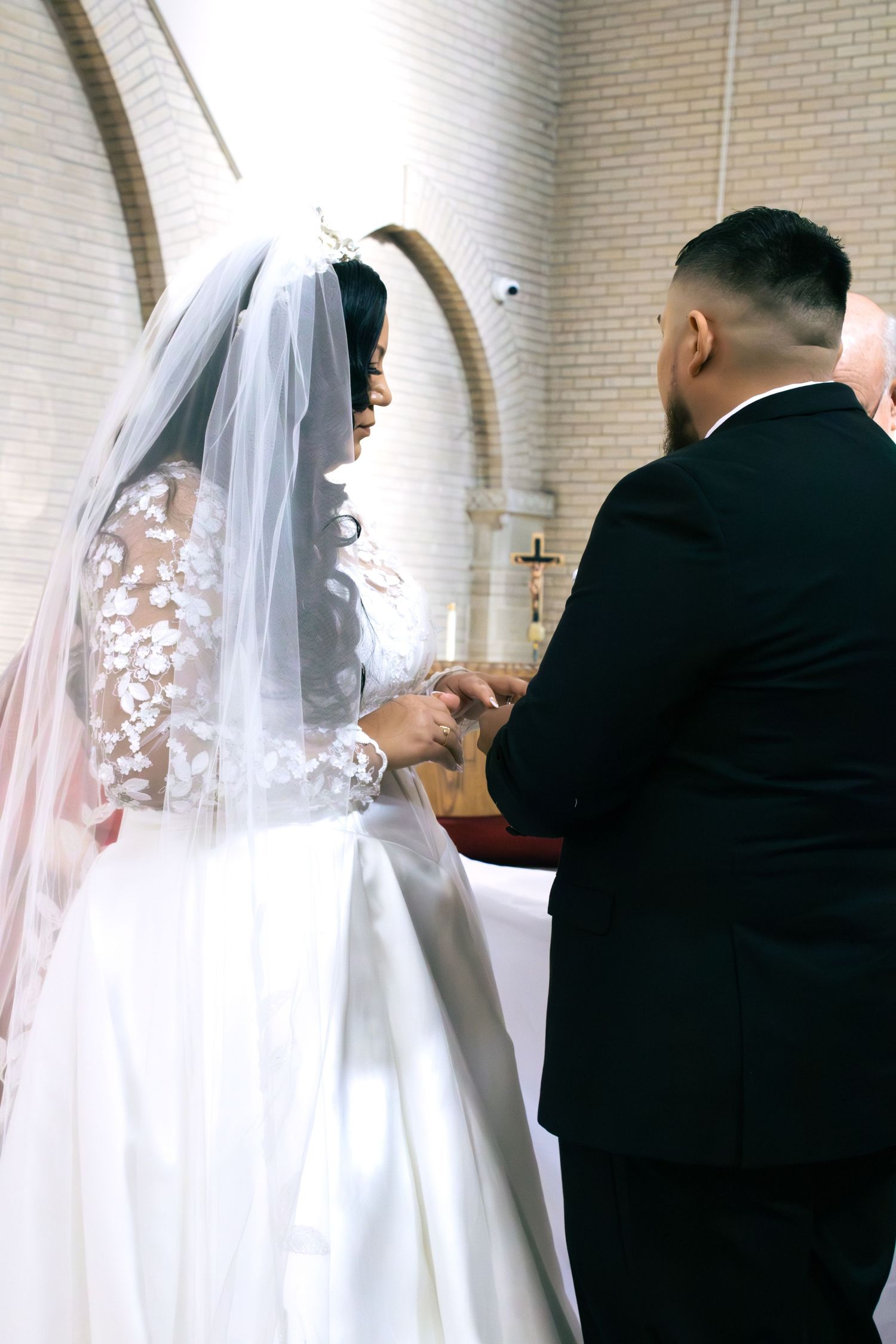 A bride in a white gown and veil participates in a traditional church wedding ceremony.
