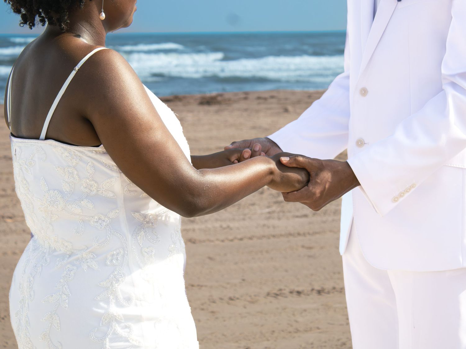 Beach wedding ceremony moments with ocean waves in background.