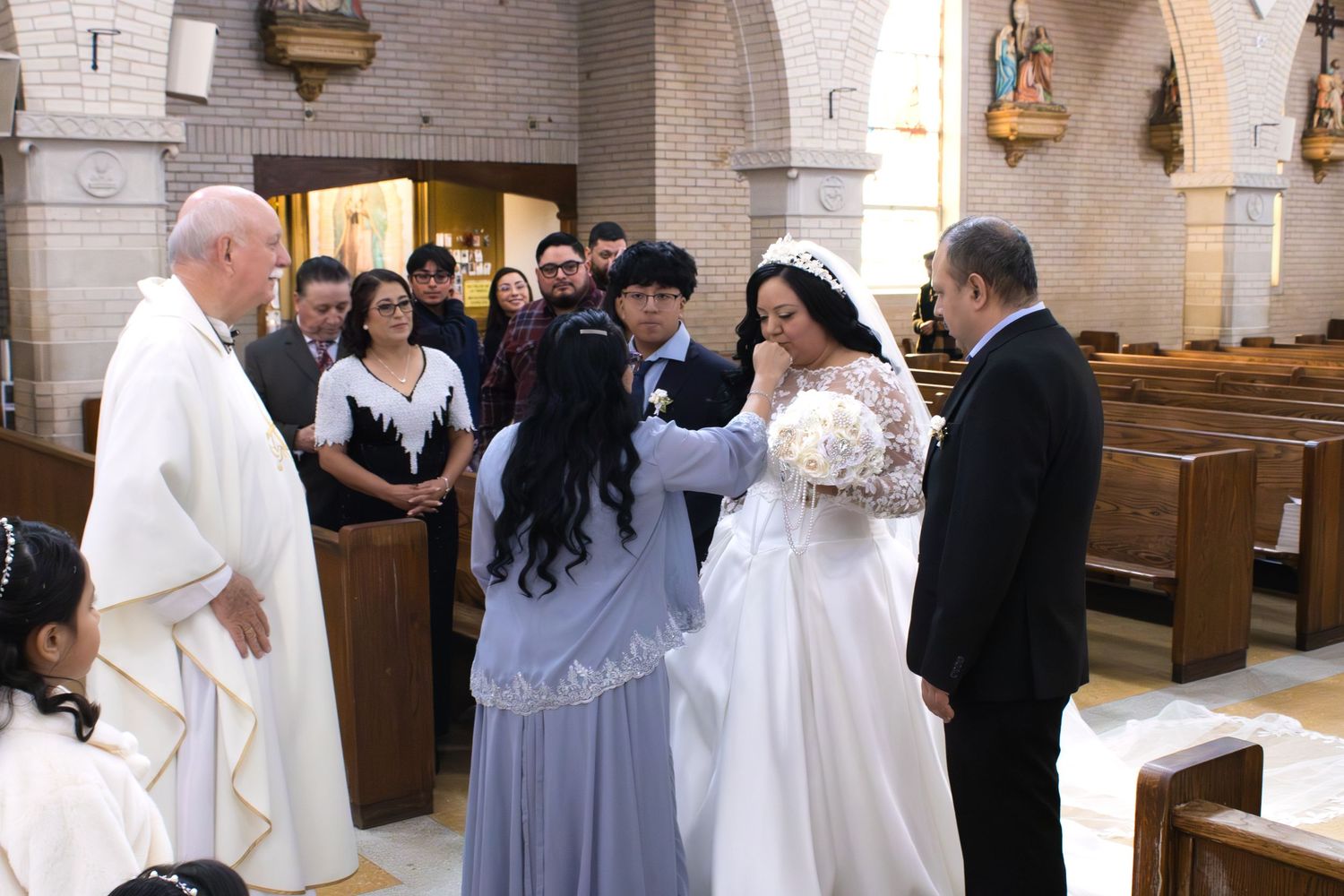 A Catholic wedding ceremony takes place in a church with stained glass windows and traditional architecture.