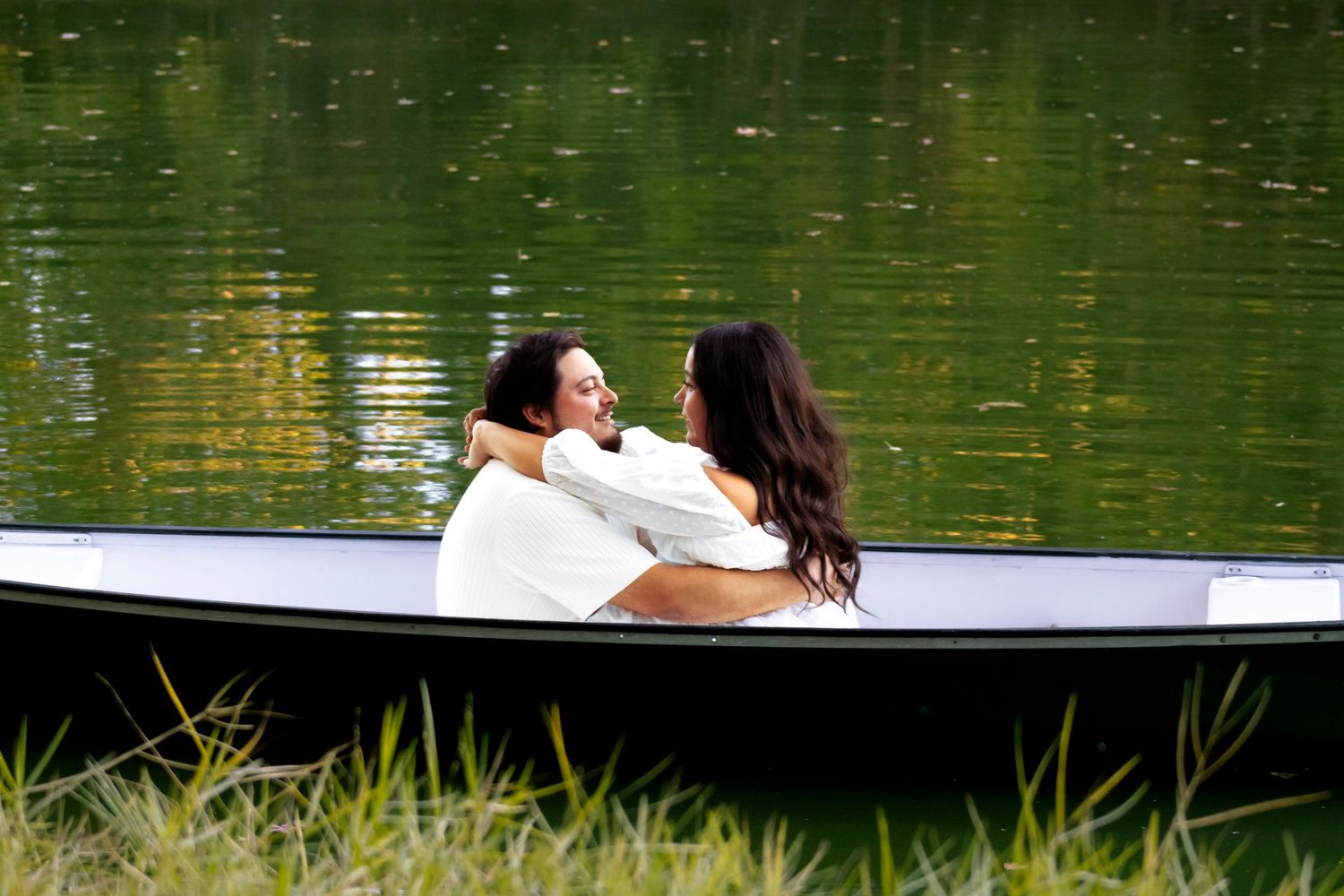 A romantic couple lounging in a boat on calm green waters.