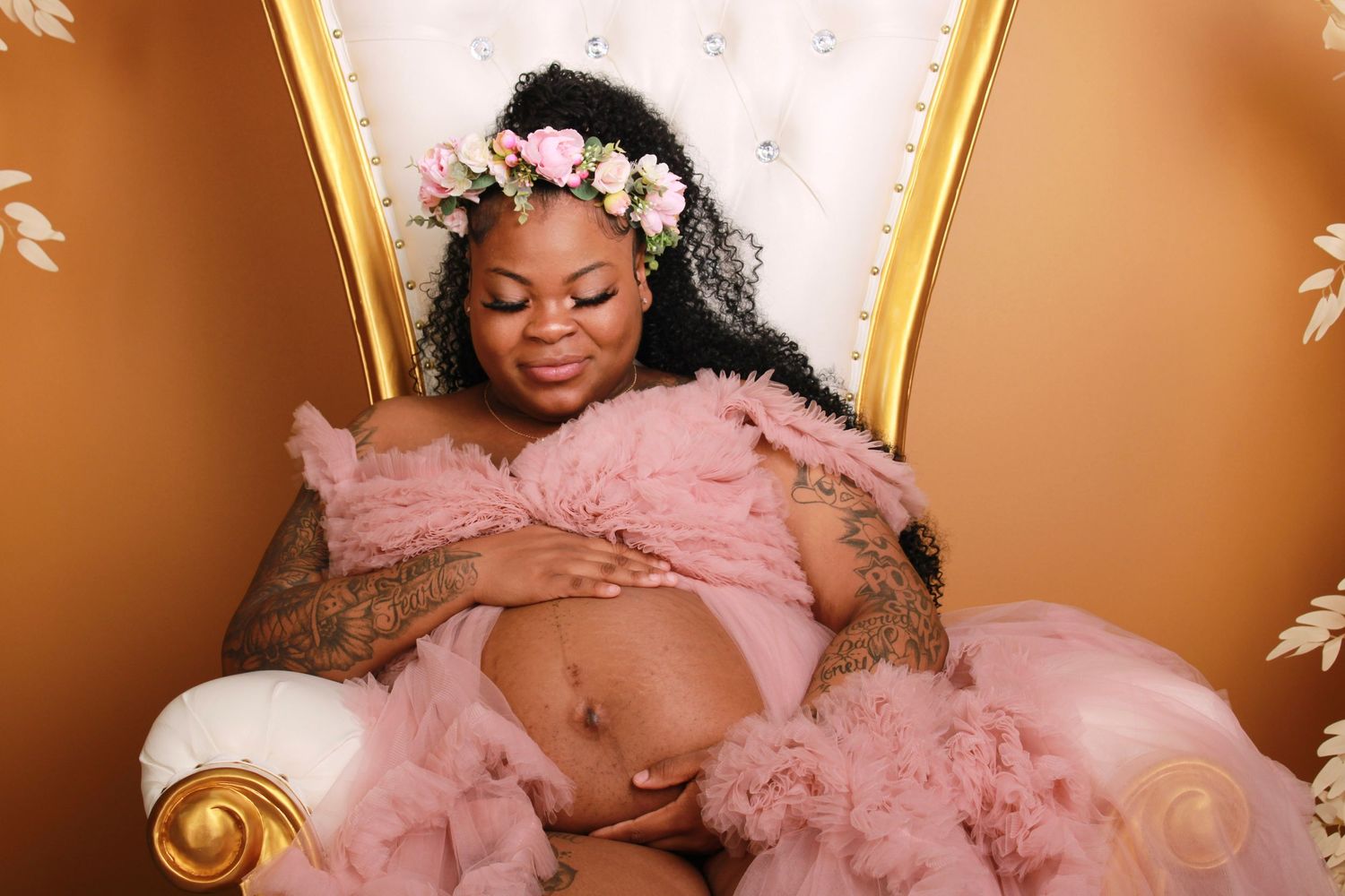 Elegant maternity portrait featuring pink tulle gown and floral decorations.