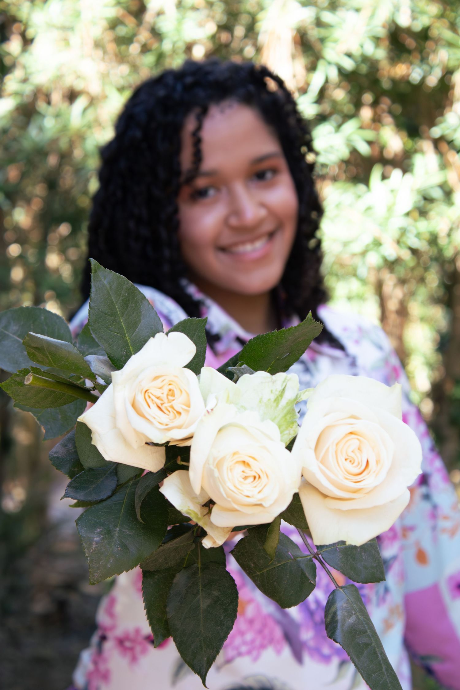 Cream colored roses being held against a green leafy background.