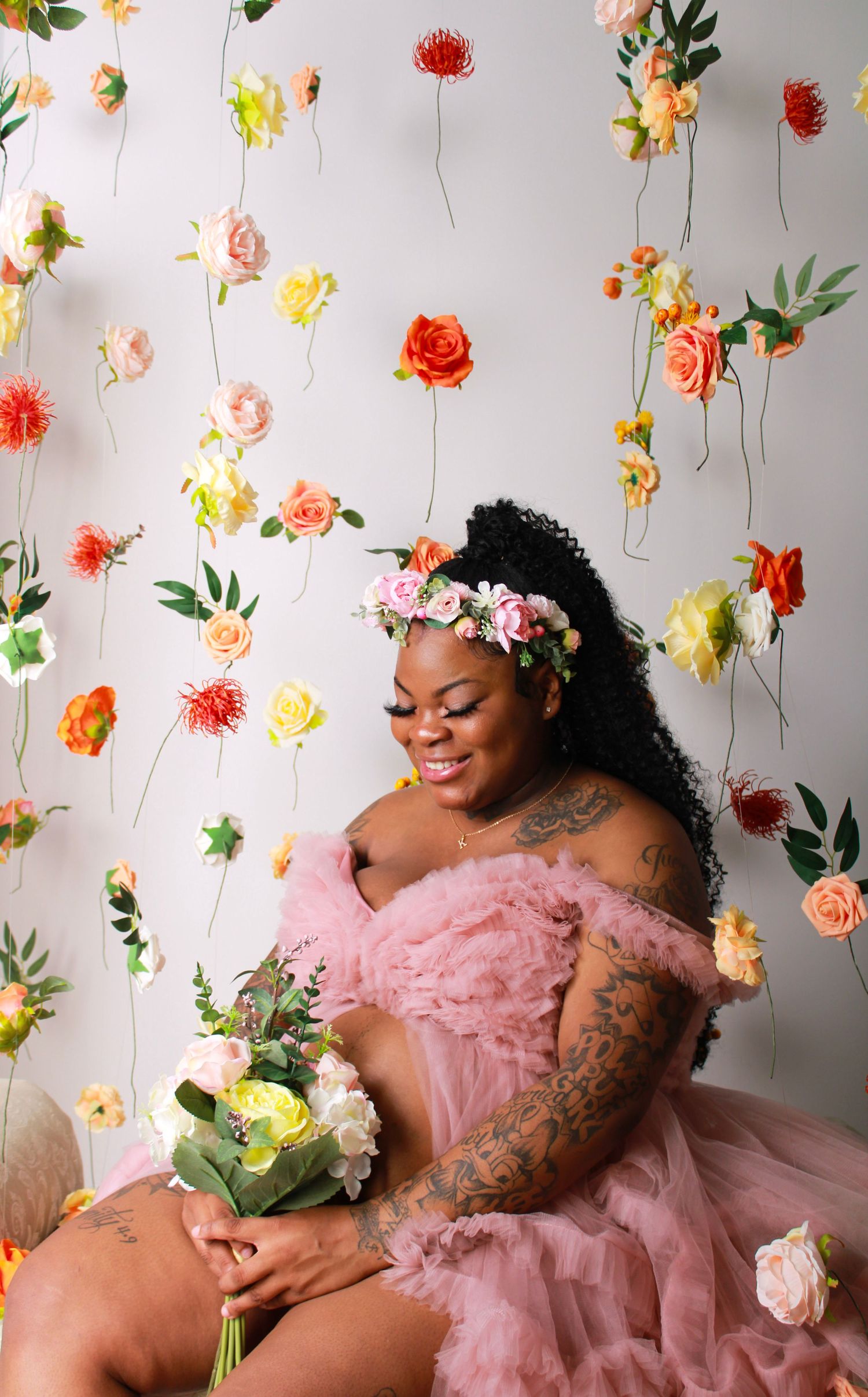 Maternity photoshoot with hanging floral decorations and pink tulle dress.