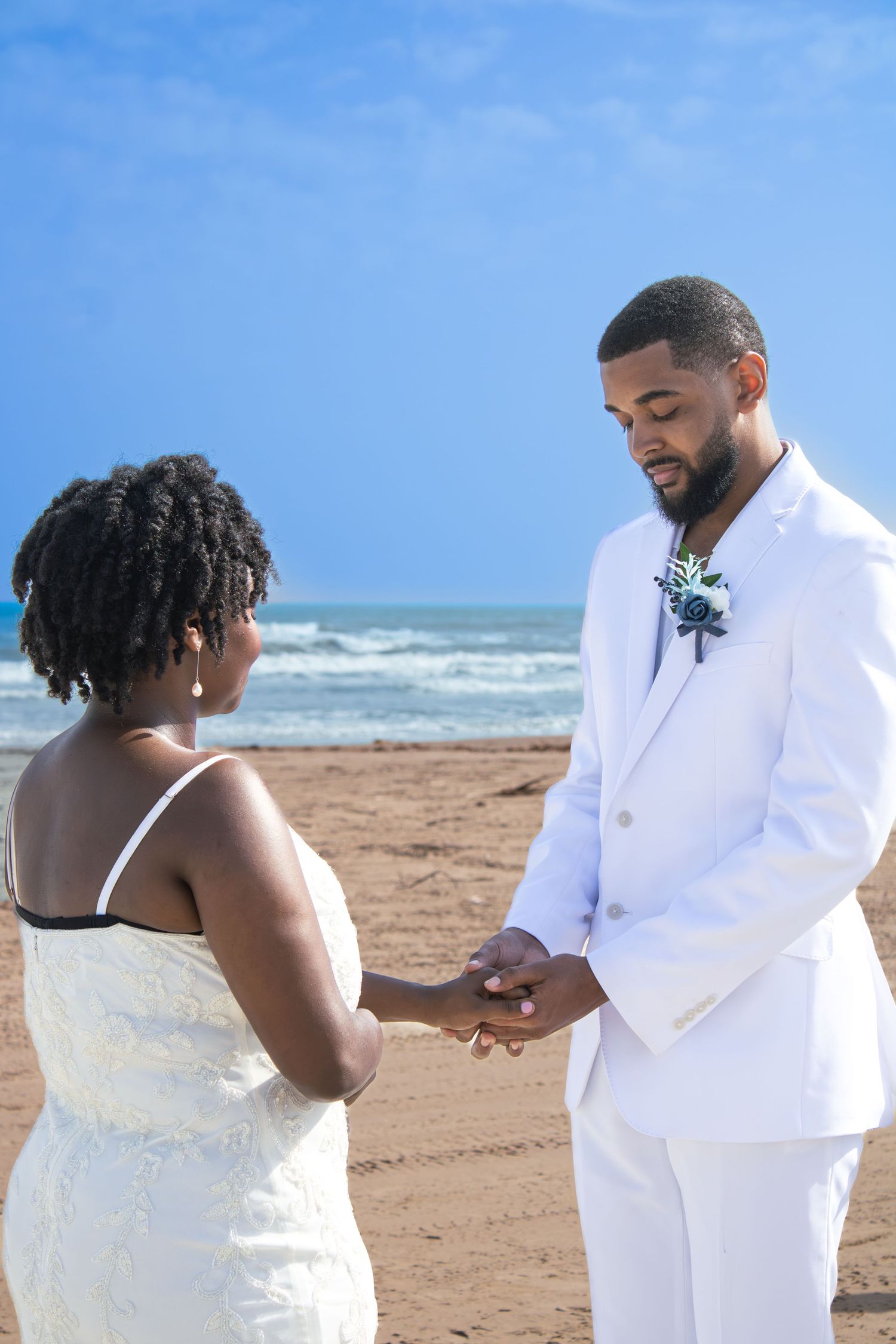 Beach wedding ceremony with waves and blue sky in background.
