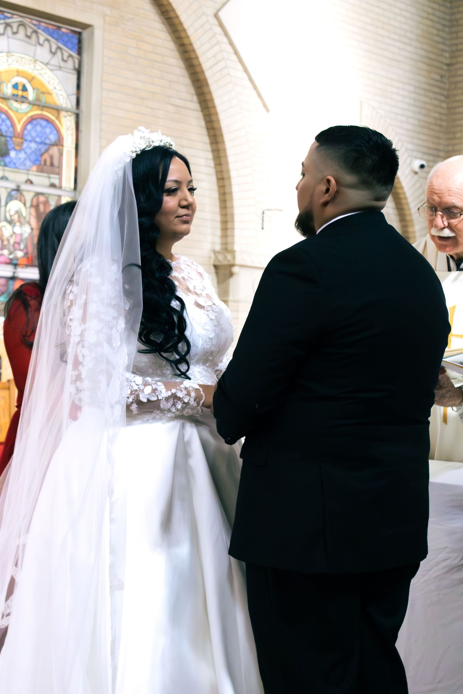 A wedding ceremony procession moves through a church with decorative brick walls and stained glass.