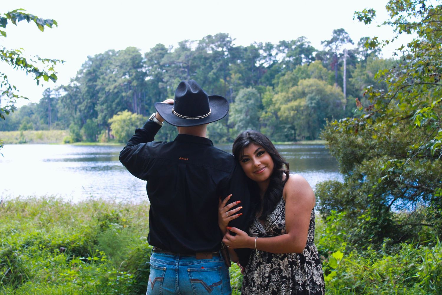 Couple embracing while enjoying scenic lake views on a sunny day.