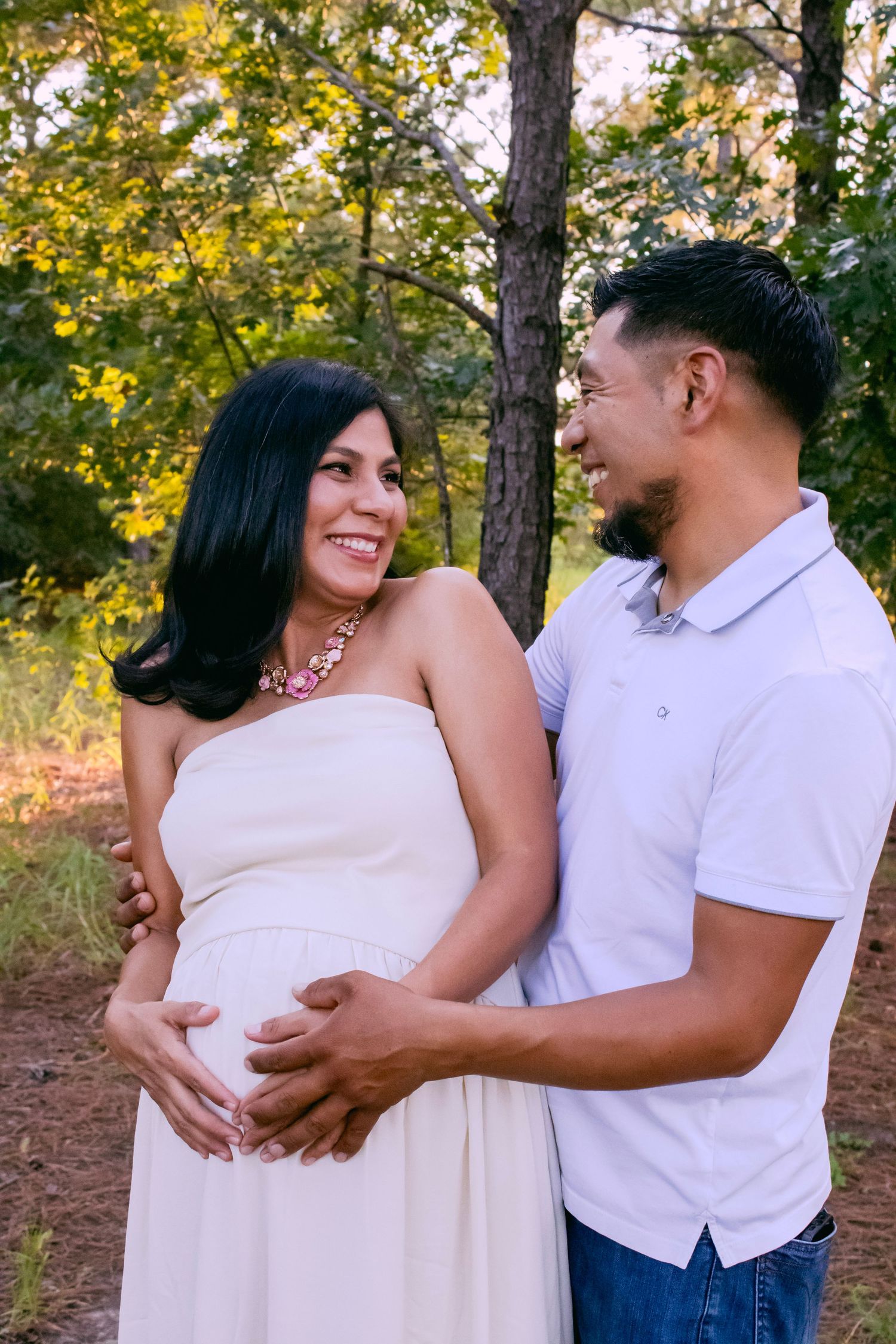 Maternity photo session capturing tender moments between couple in autumn forest setting.