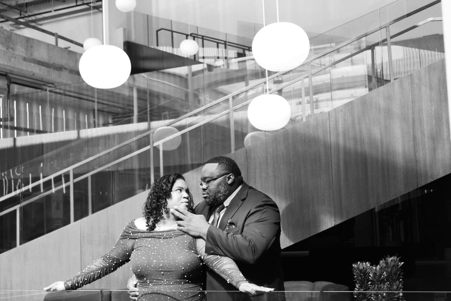 A couple dances together in a modern space with round white ceiling lights.