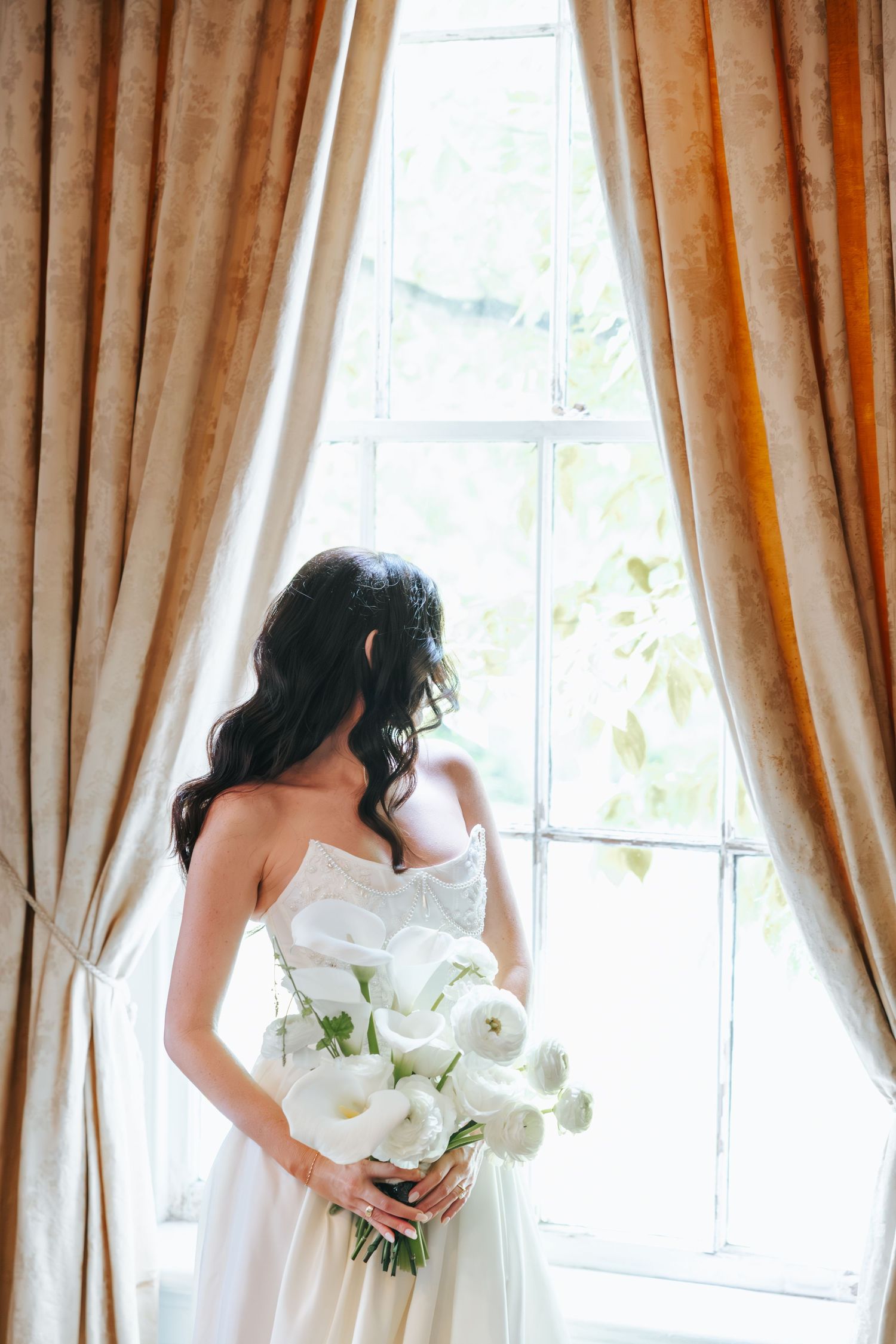 A row of three identical bridal portraits with white wedding dresses and elegant cascading orchid bouquets by sunlit windows.