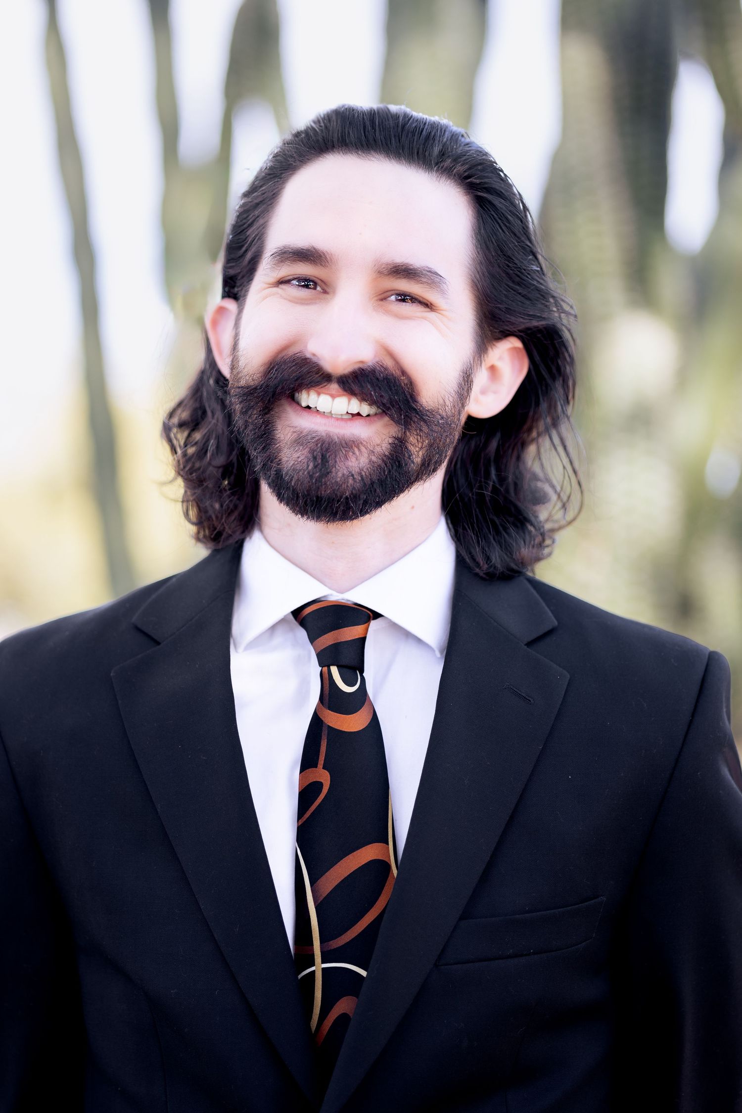 A sequence of photos showing someone in a black suit and striped tie smiling against a blurred forest background.