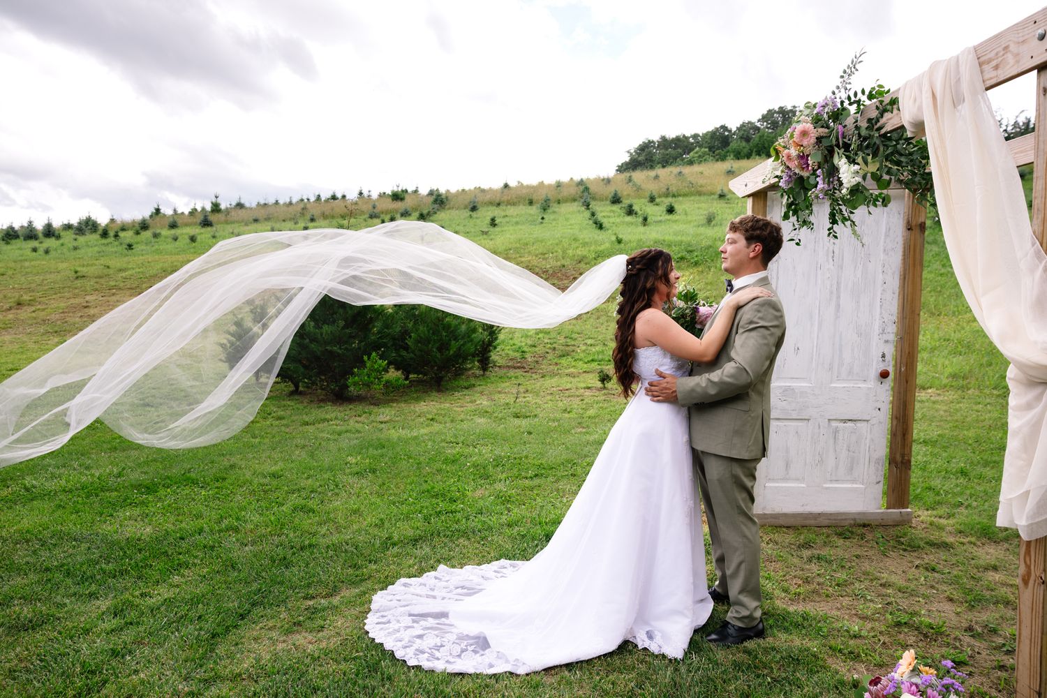 A wedding photo sequence shows romantic moments on a grassy hillside with flowing white veils catching the breeze. East Tennessee Wedding.