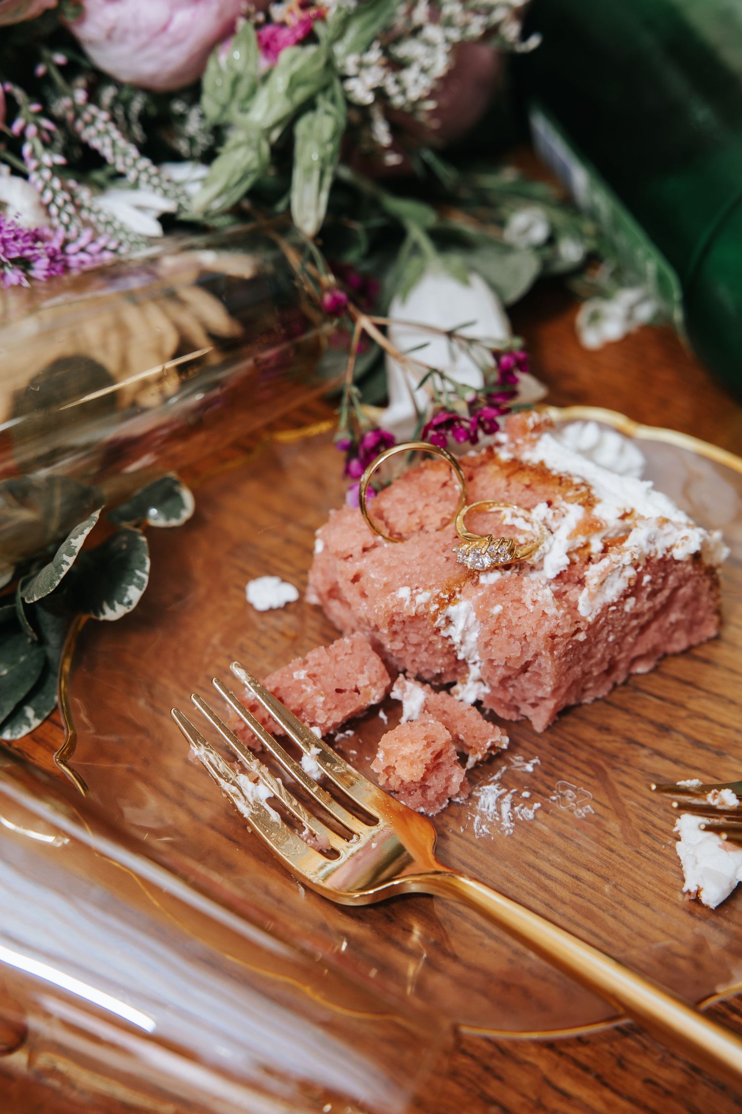 A sequence of chocolate cake being eaten with a gold fork on a wooden surface decorated with pink and white flowers.