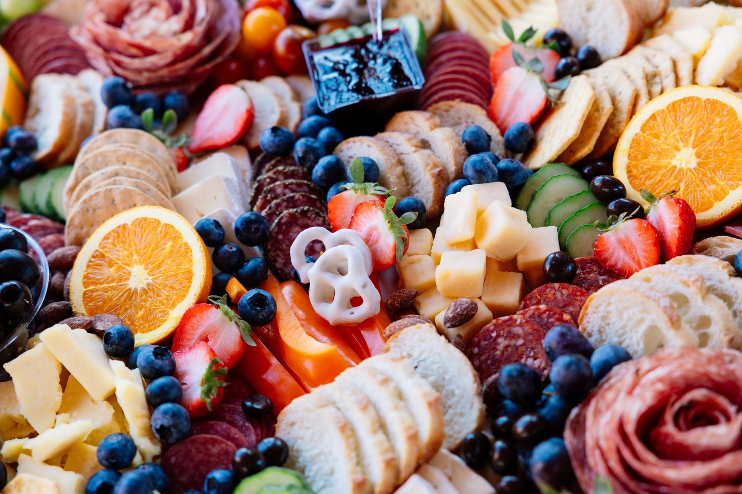 Colorful charcuterie board with meats, cheeses, fresh fruits, and berries arranged in an artistic display.