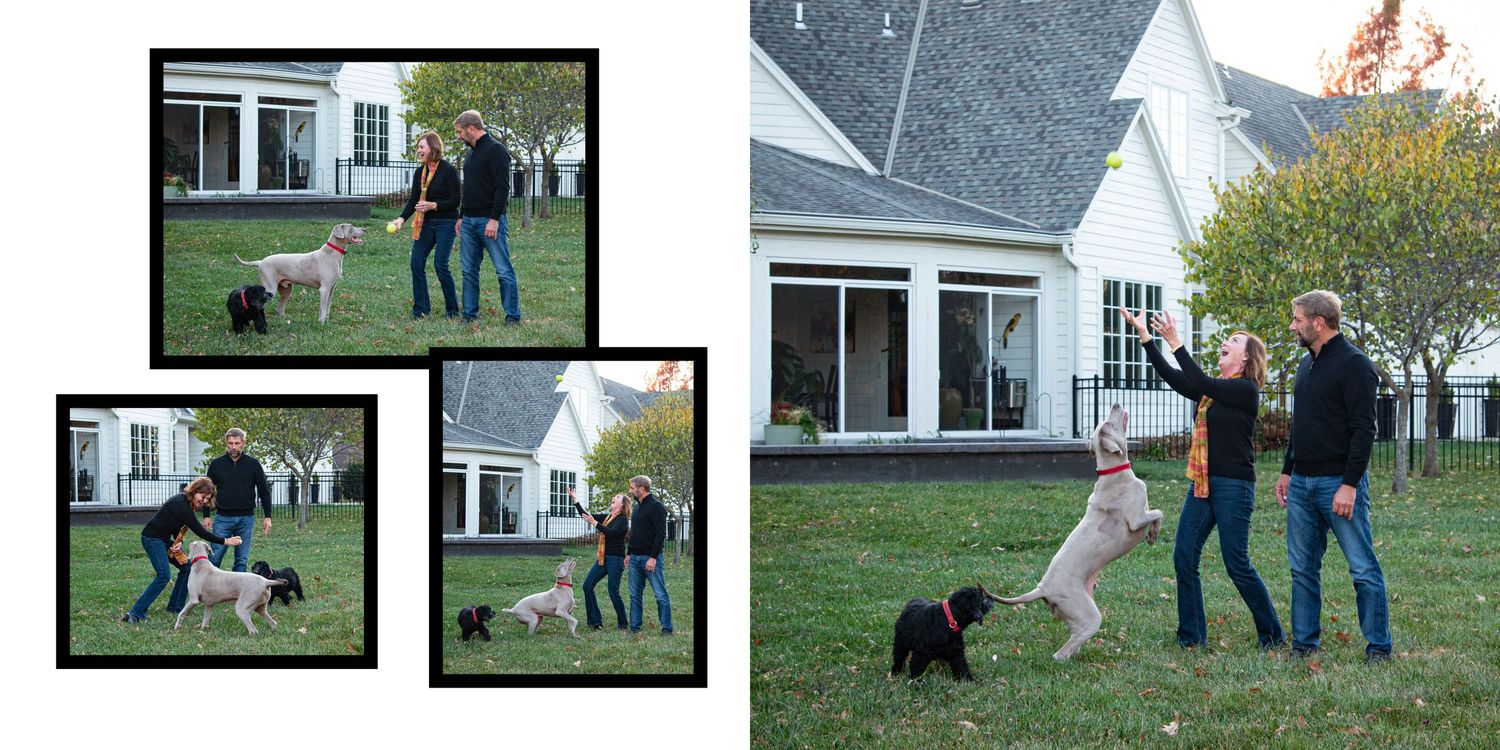 Couple playing with two dogs on green lawn outside white farmhouse in autumn.