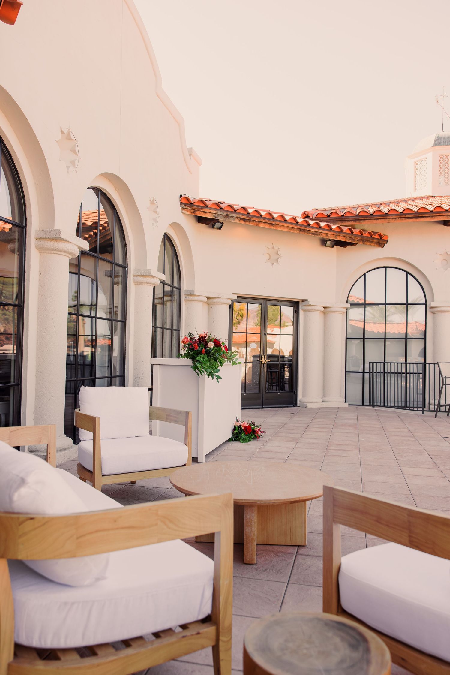 Mediterranean-style terrace with white arches, tiled floors, and modern lounge furniture creates an elegant outdoor living space.