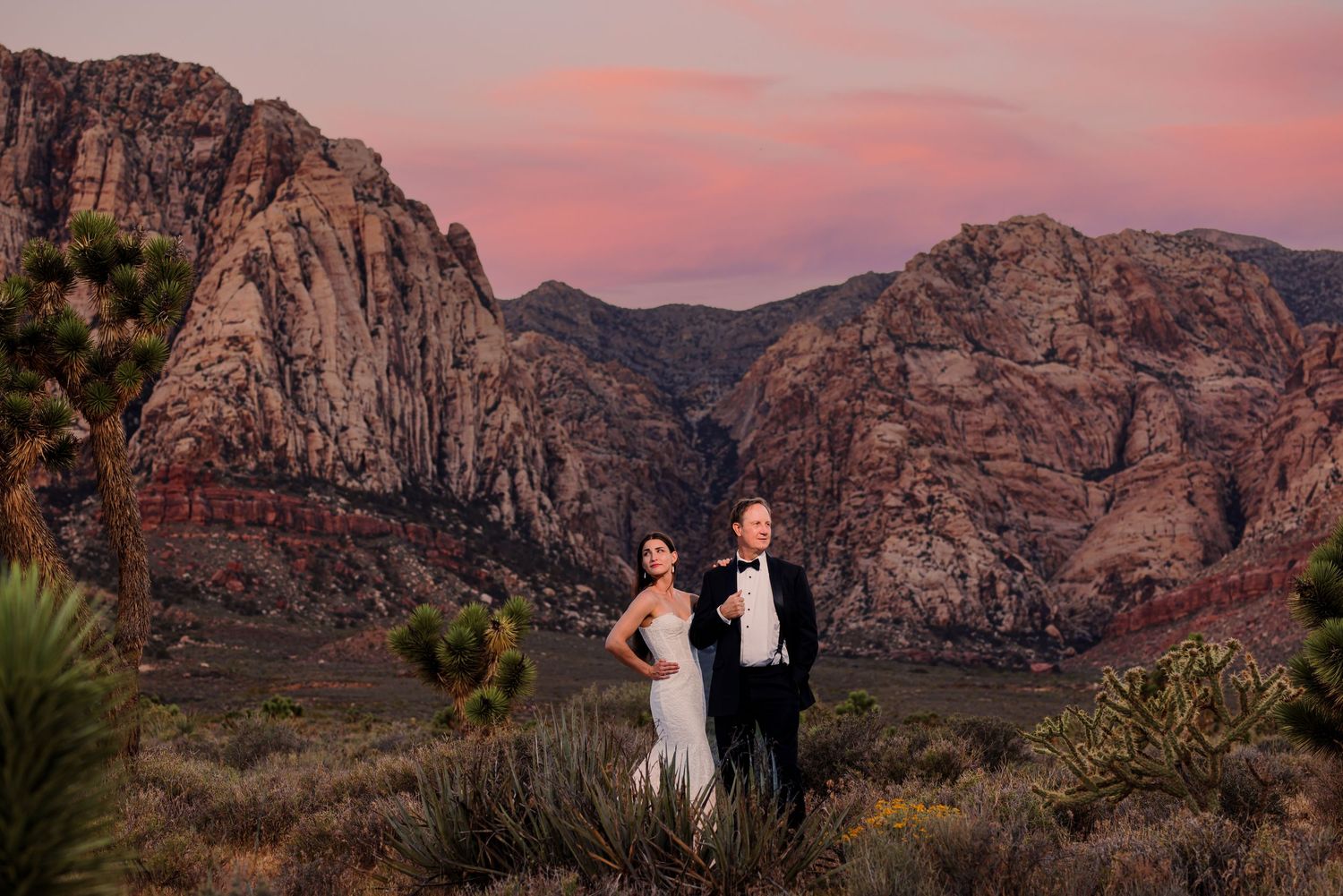 A couple poses against the dramatic red rock formations of Red Rock Canyon during sunset in Las Vegas, Nevada.