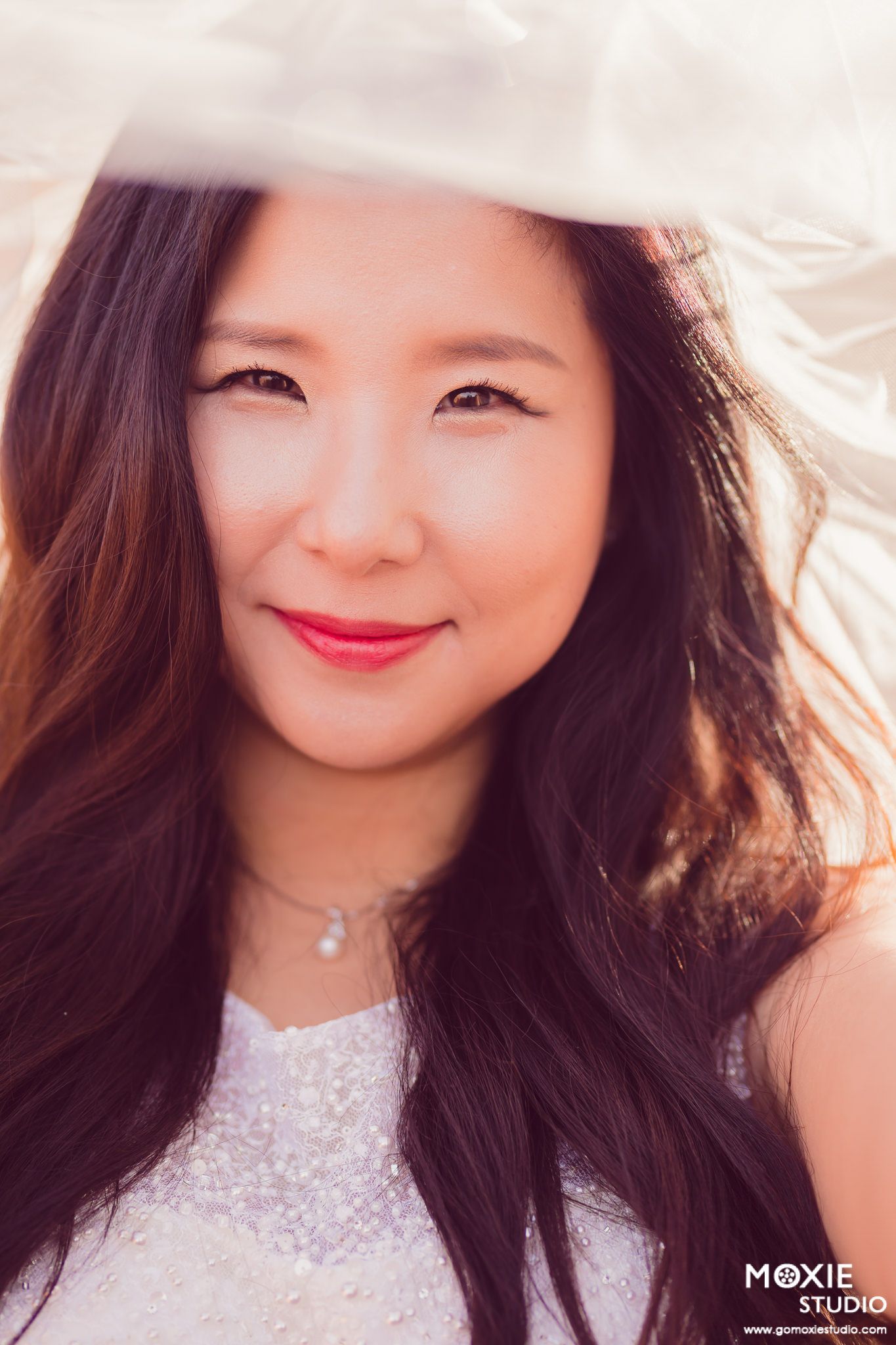 A series of five soft, dreamy outdoor portraits showing someone in a white lace dress with long dark hair and bright lipstick.