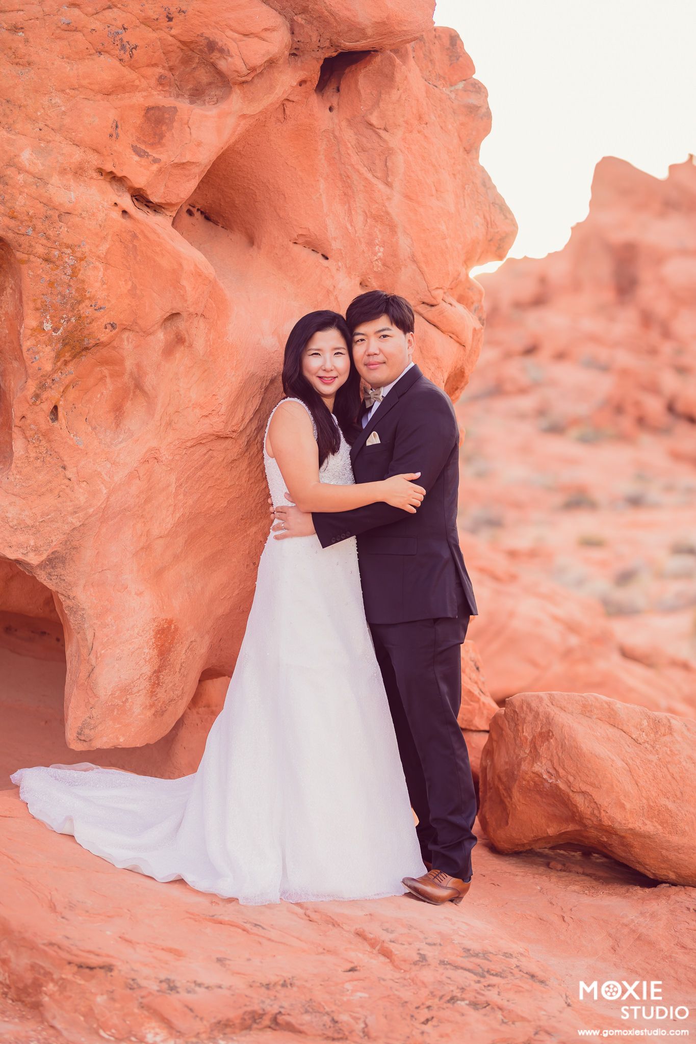 A couple in wedding attire poses together among red rock formations in Valley of Fire State Park, Nevada.