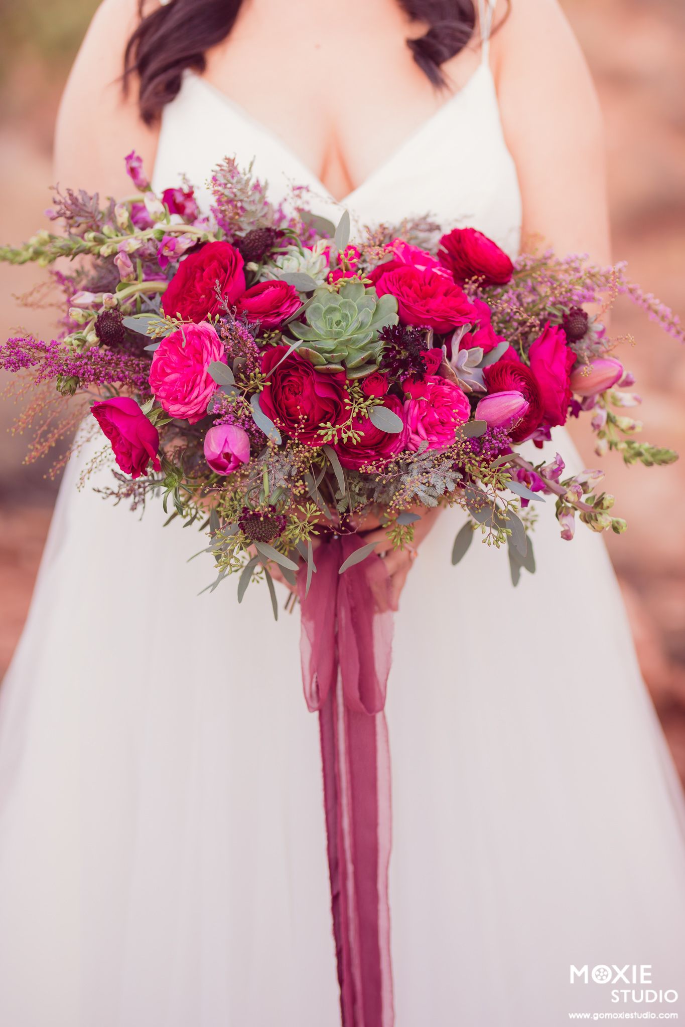 Close-up views of vibrant burgundy and pink wedding bouquets with succulents and flowing ribbons against a soft blurred background.