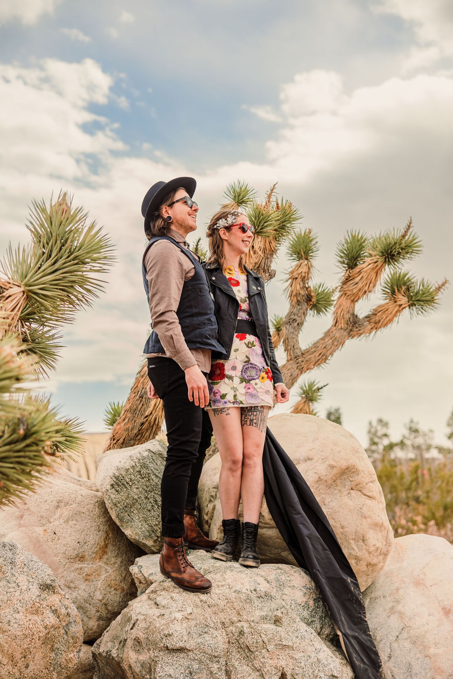 Panoramic sequence of people enjoying scenic views while standing on large desert rocks among Joshua trees.