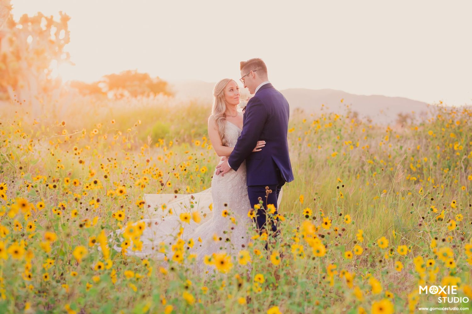 A couple shares a romantic moment in a vibrant field of yellow wildflowers at sunset at the Paiute golf course outside Las Vegas