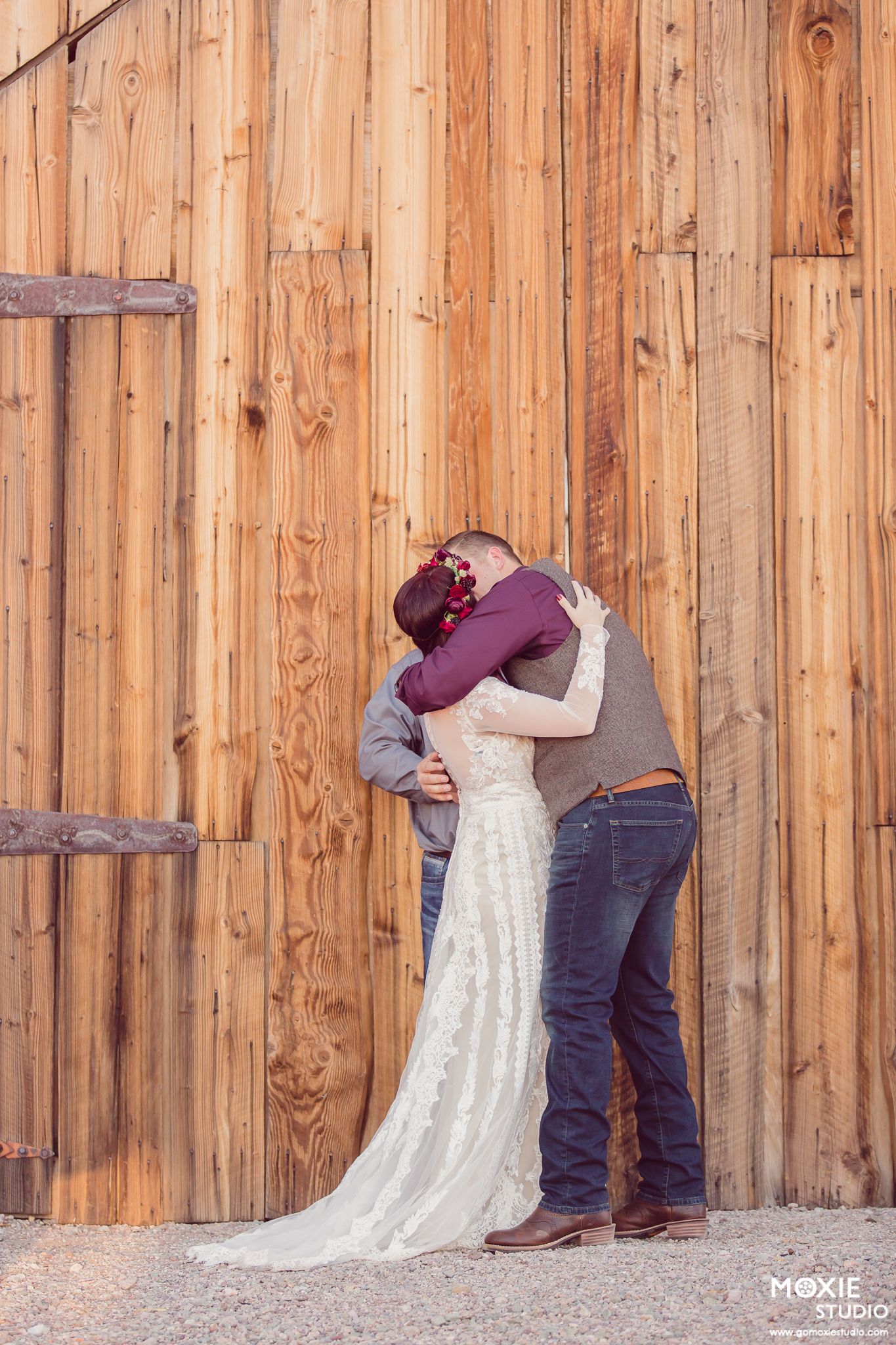 Rustic wooden wall panels create a backdrop for a romantic scene with vintage-inspired wedding attire.