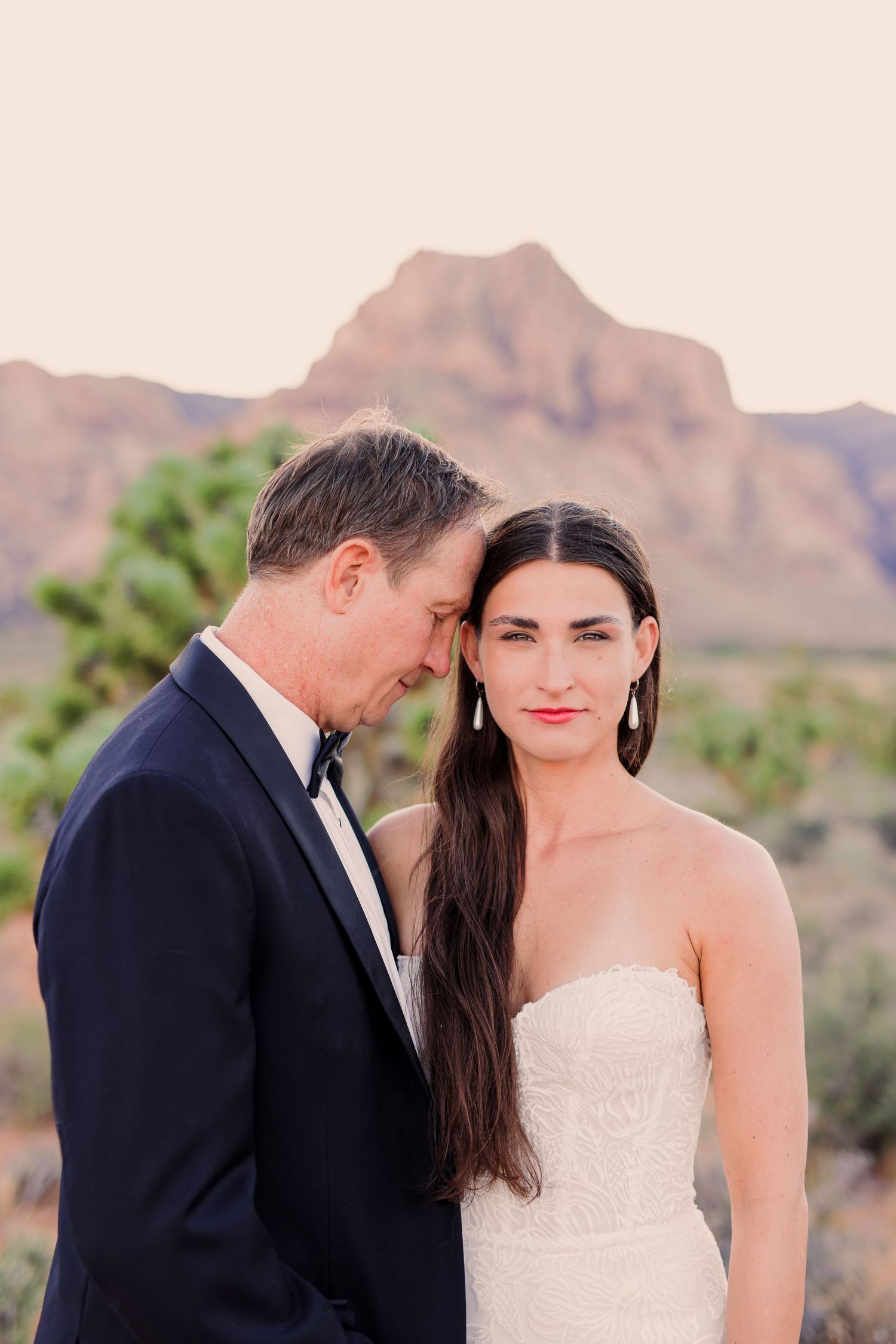 A couple shares intimate moments during their desert wedding photoshoot with mountains in the background.