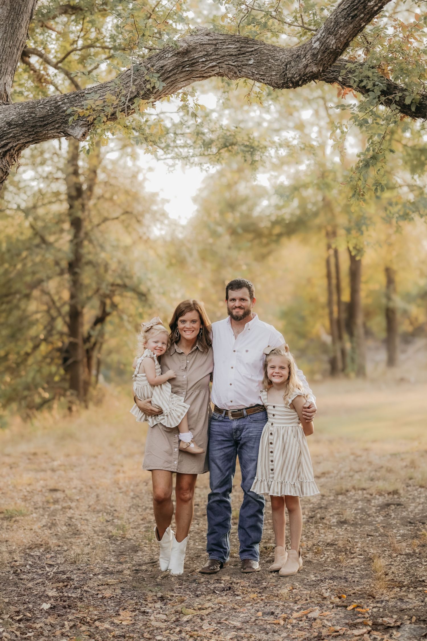 Family of four enjoying a cozy moment together in a blanket of colorful fall leaves during a photo session