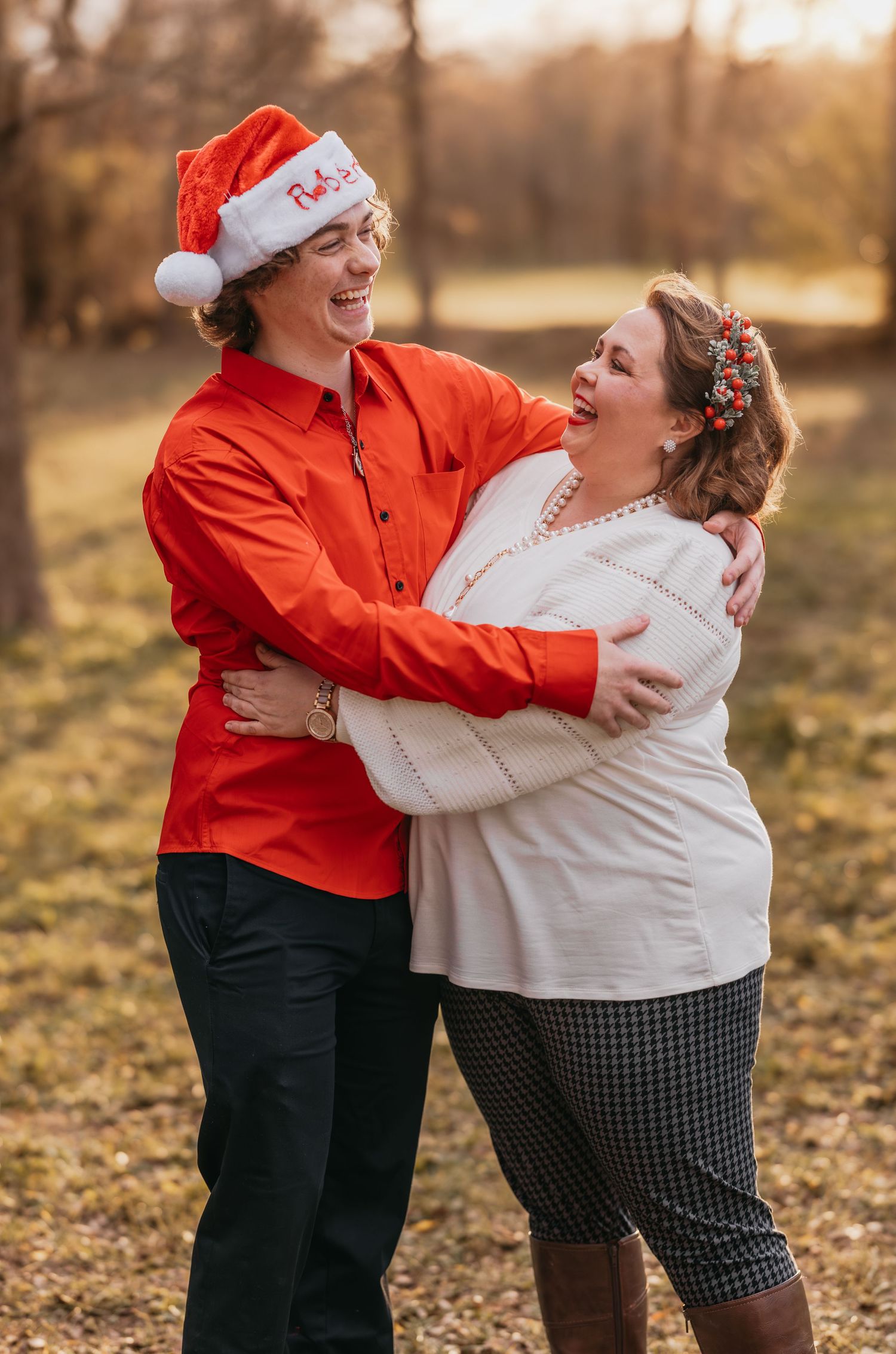 Mom and son wearing Santa hats smiling at each other during Christmas mini session in Salado, Texas