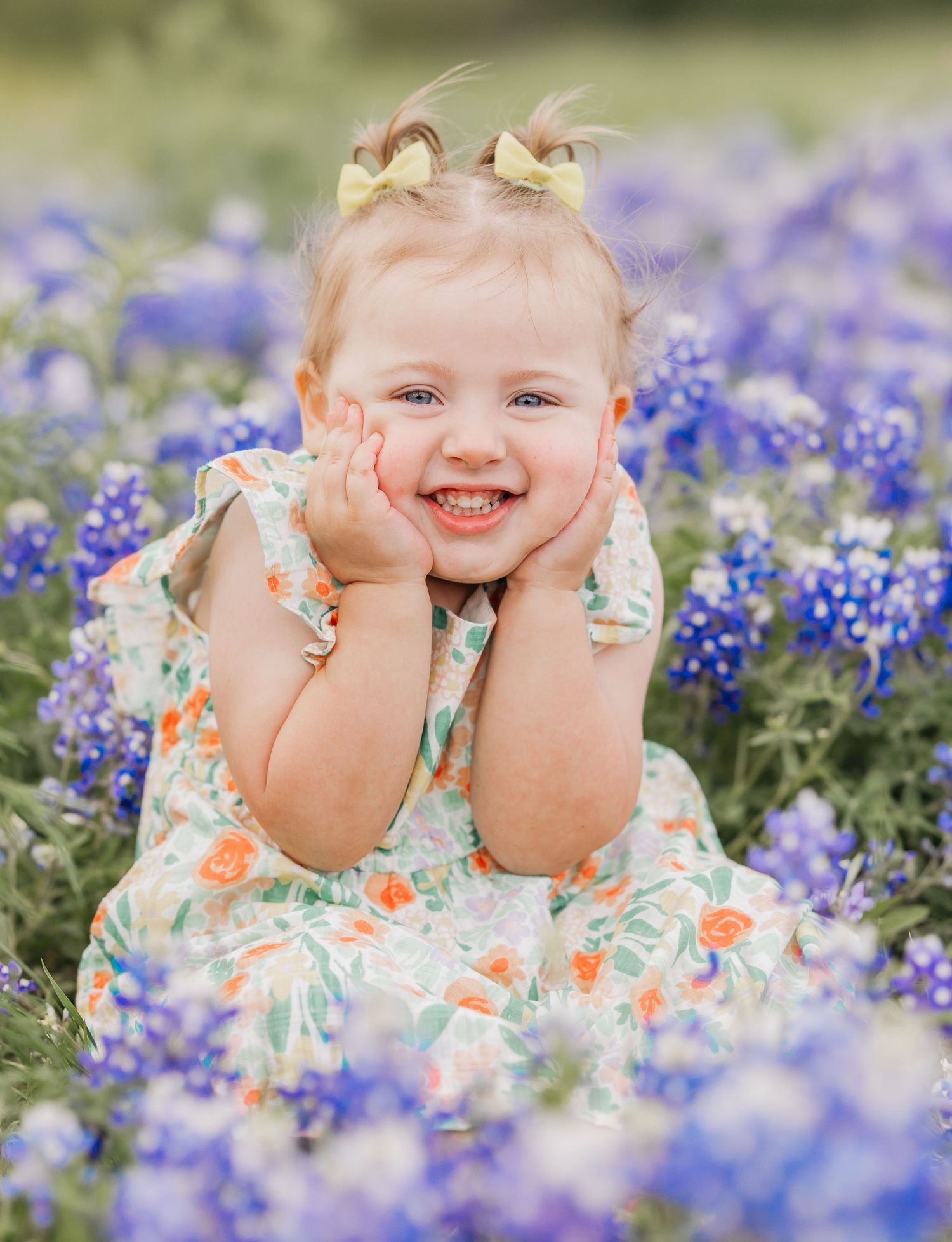 Cute little girl smiling while sitting in a field of vibrant bluebonnets in Central Texas