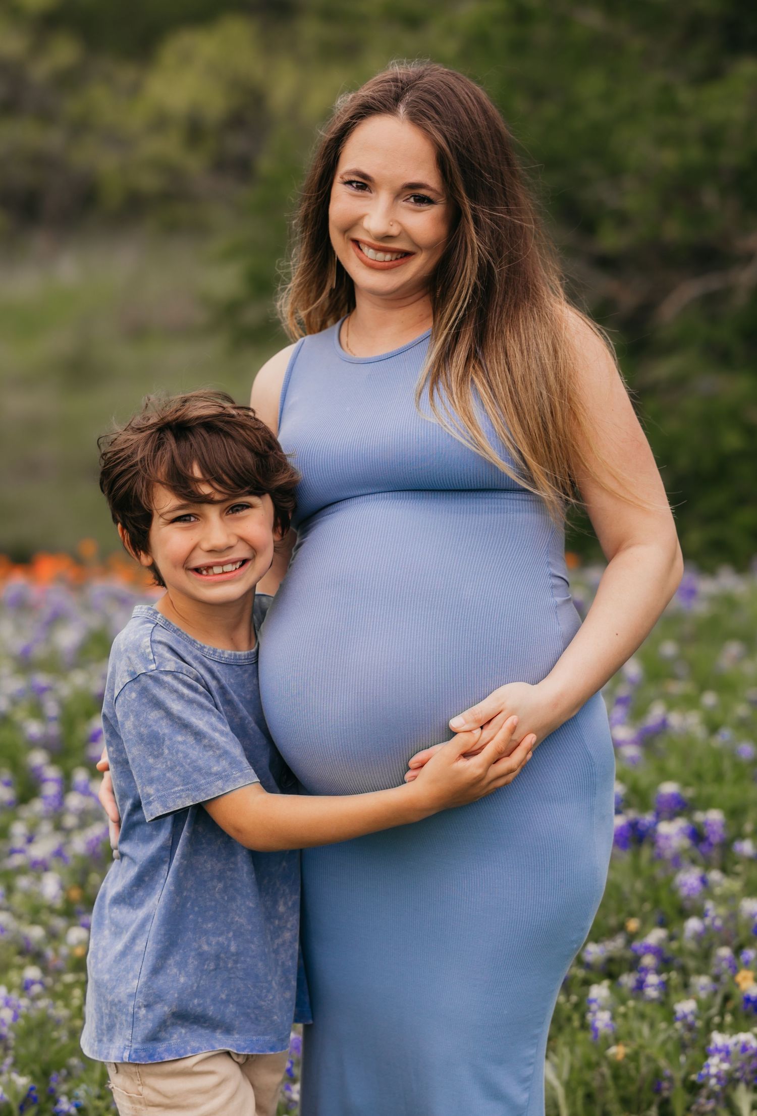 Pregnant woman in a flowy dress posing in a vibrant field of bluebonnets in Central Texas during a maternity photo session