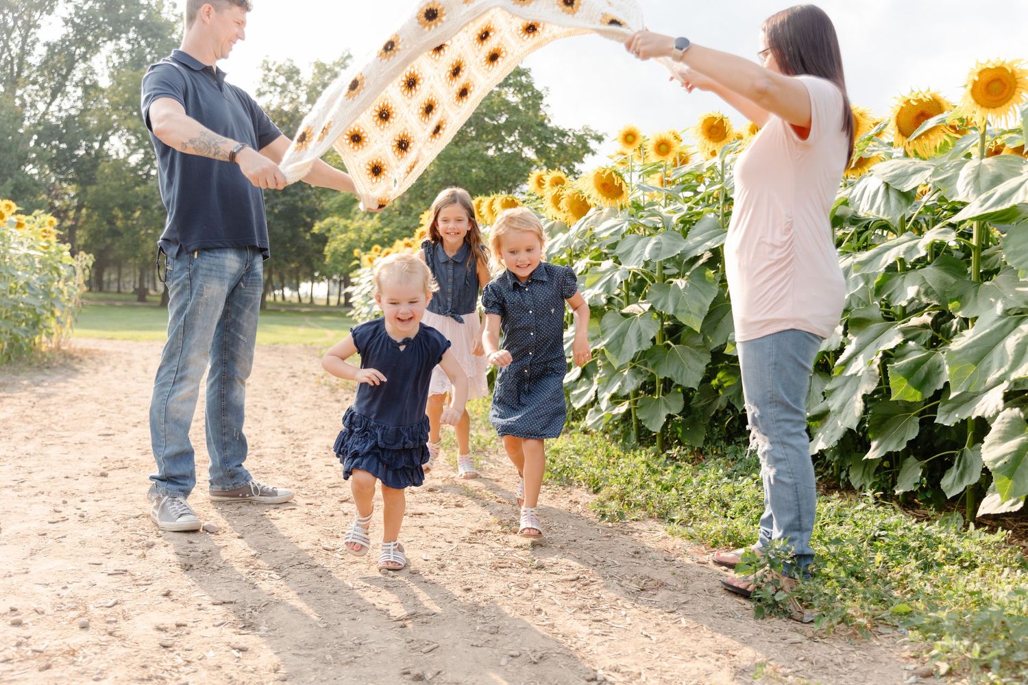 A family walks through a vibrant sunflower field on a sunny summer day, creating a joyful outdoor moment together.