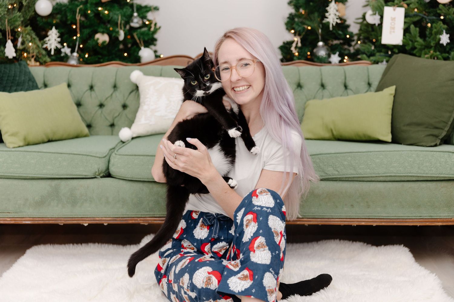 Brieanna sitting on the floor with Rupert her black cat in front of a christmas tree.