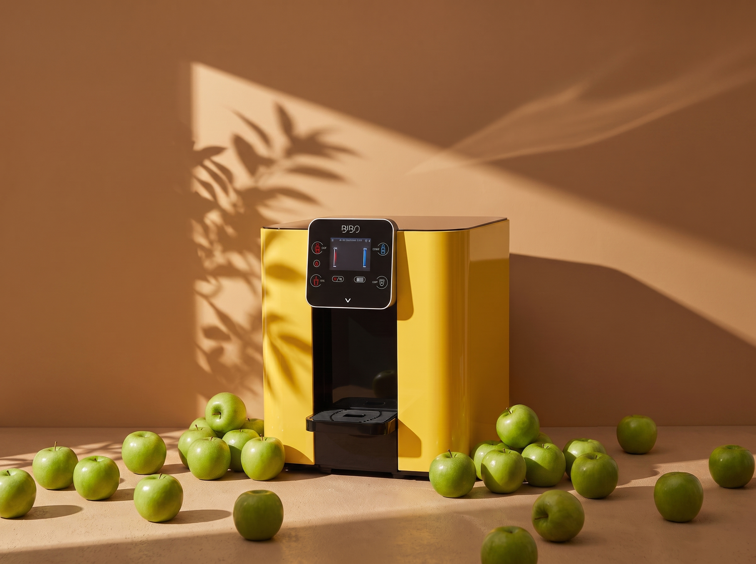 Yellow water dispenser surrounded by green apples on a warm beige background with soft plant shadows.