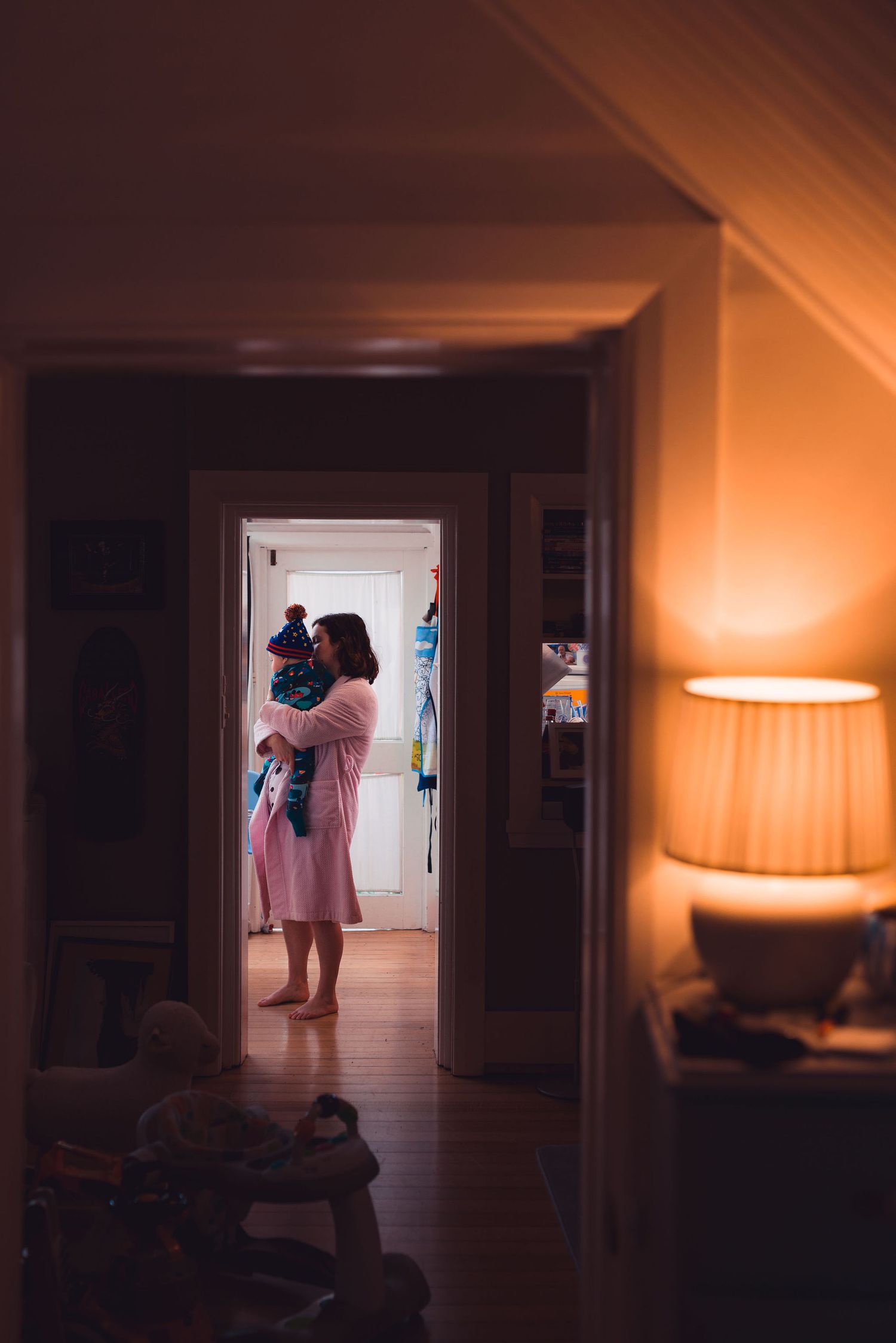 A dimly lit hallway sequence showing silhouettes and warm lighting creating a moody atmospheric interior scene.