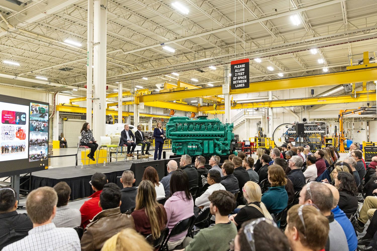 A large crowd of people wait in a long line inside a warehouse-style retail store with yellow beams overhead.