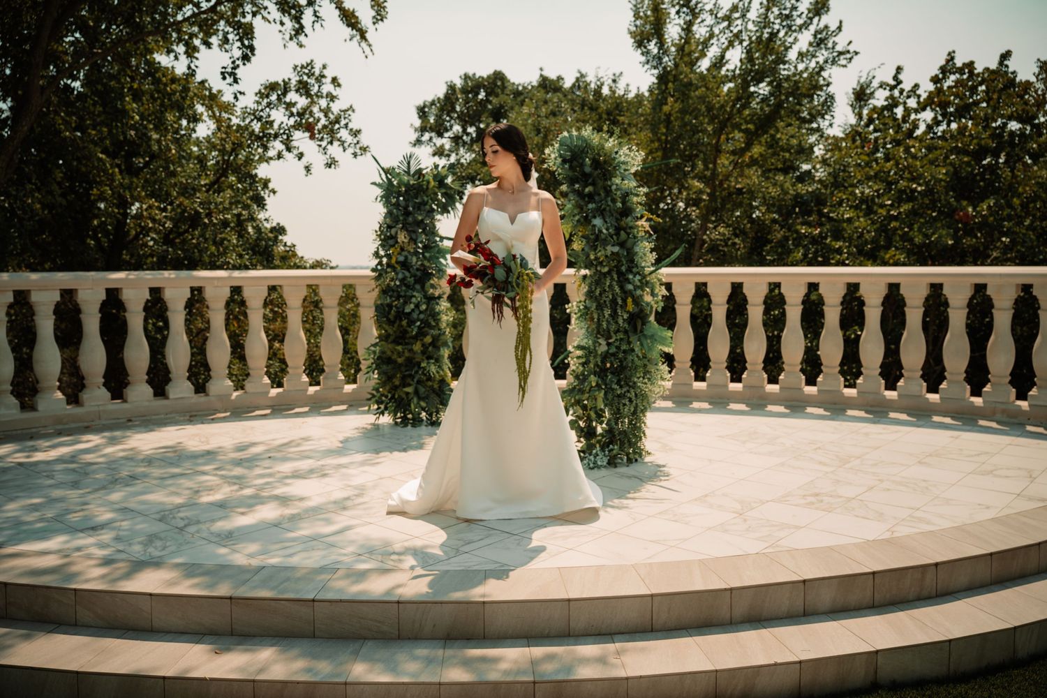 Elegant bridal portrait at the alter with dark and moody florals and greenery arches behind the bride