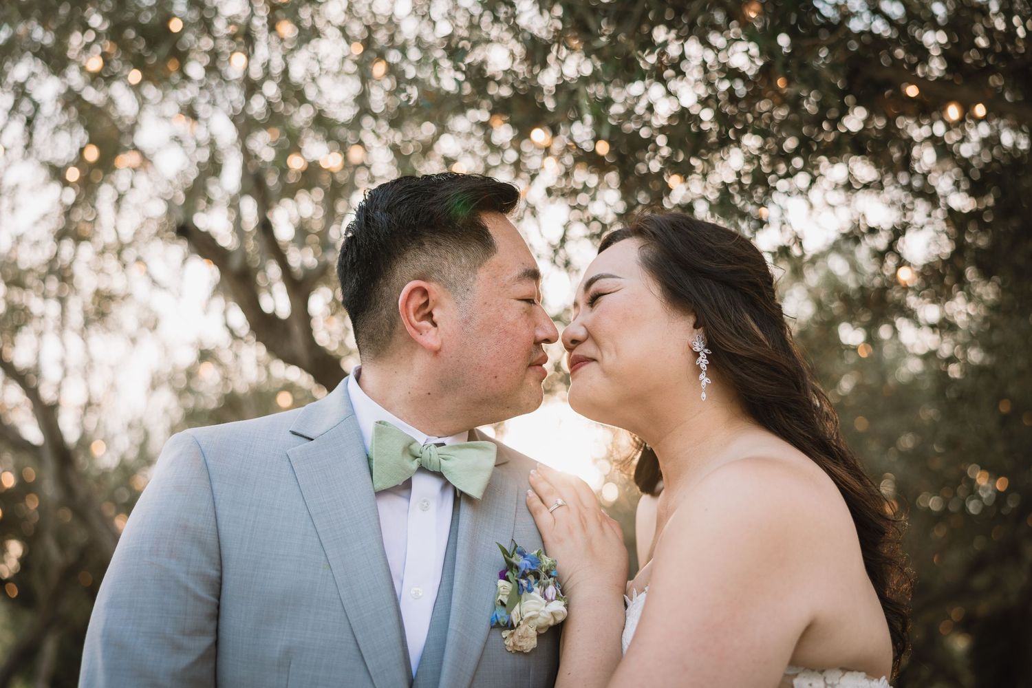 A tender moment between a couple in wedding attire against a soft natural background.