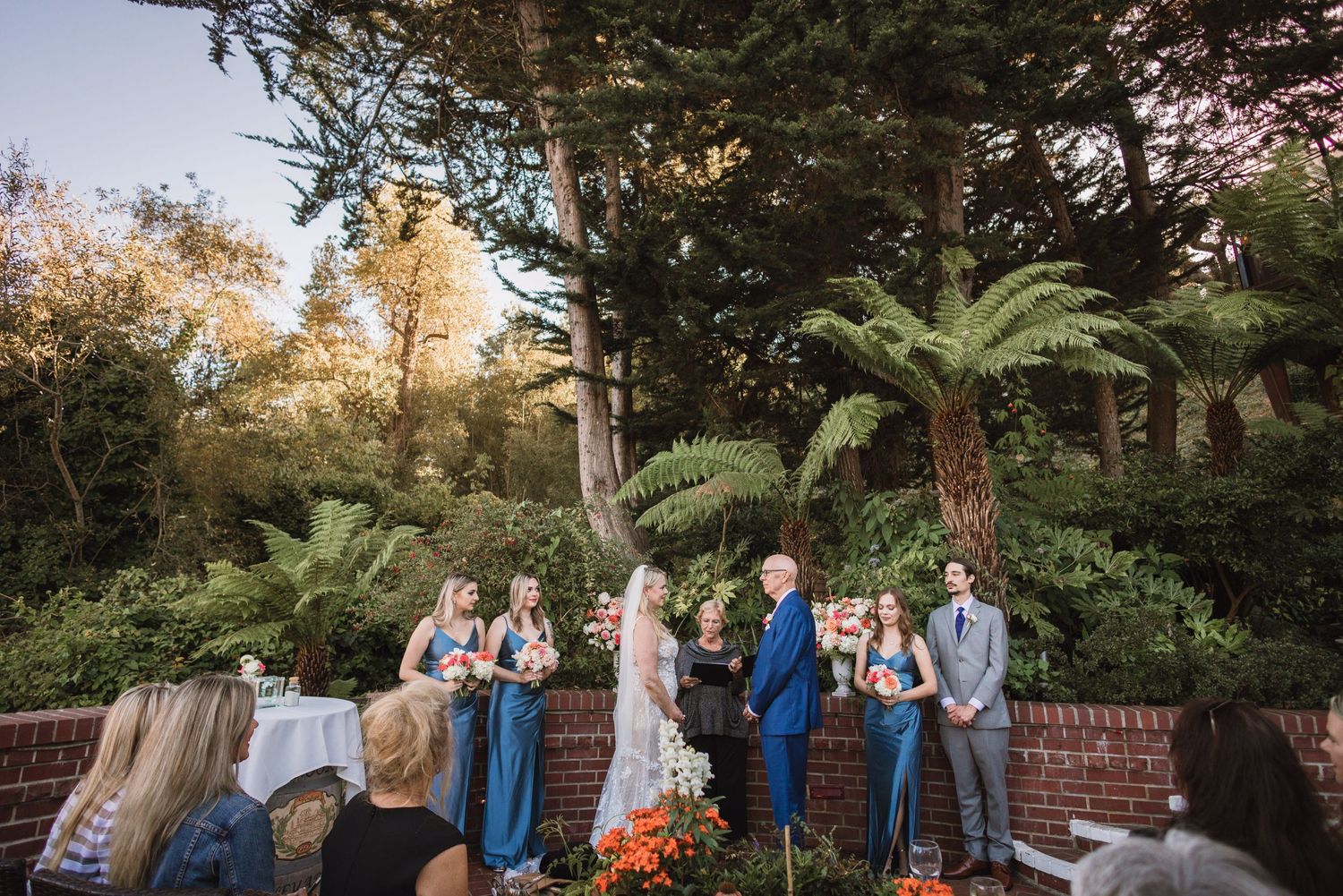 Wedding party gathered in a lush garden setting during golden hour.