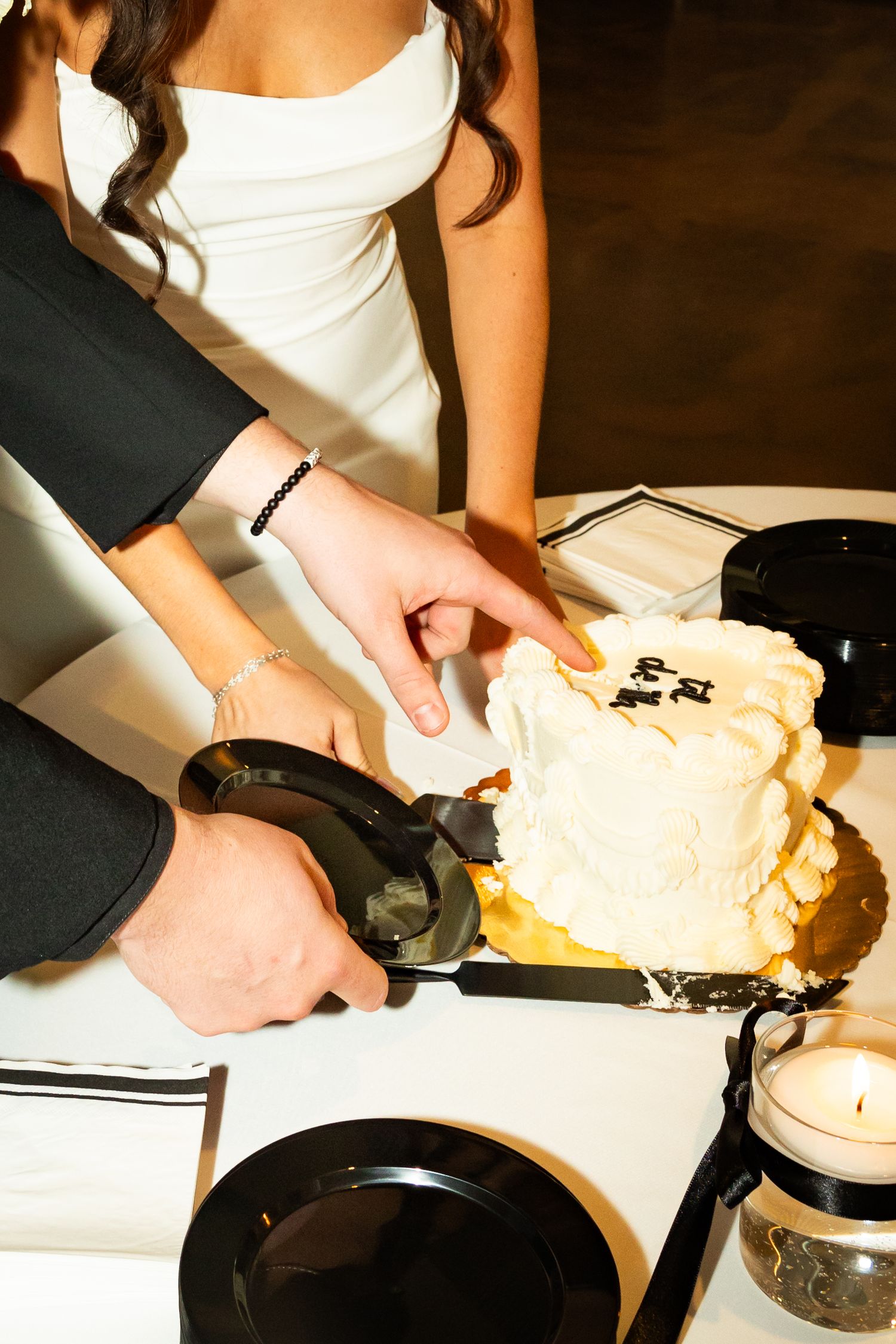 Hands spread and knead a large portion of dough on a dark countertop surface.