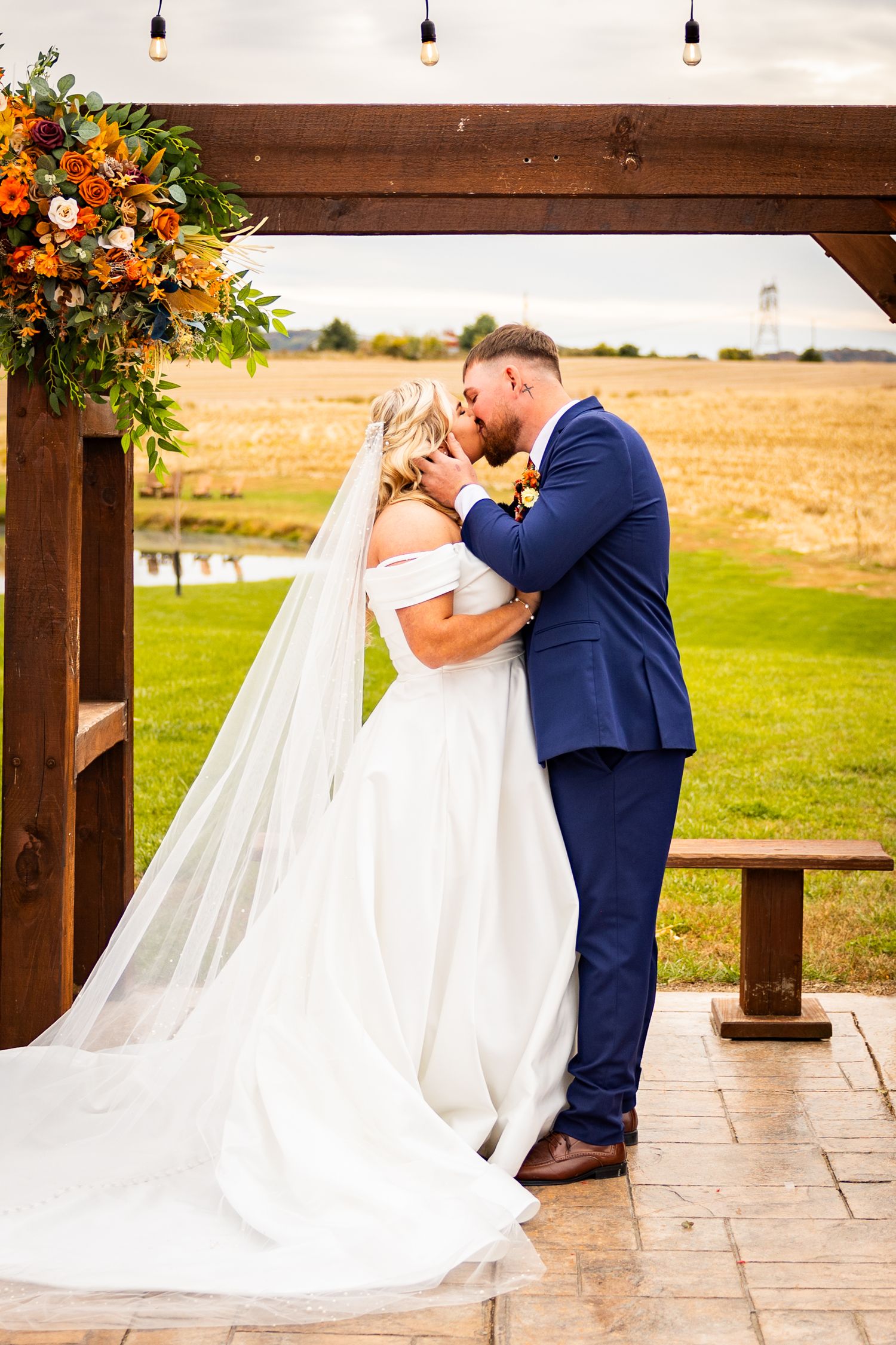 A romantic wedding moment under a wooden arch at Riser Barn in Kingston, OH.