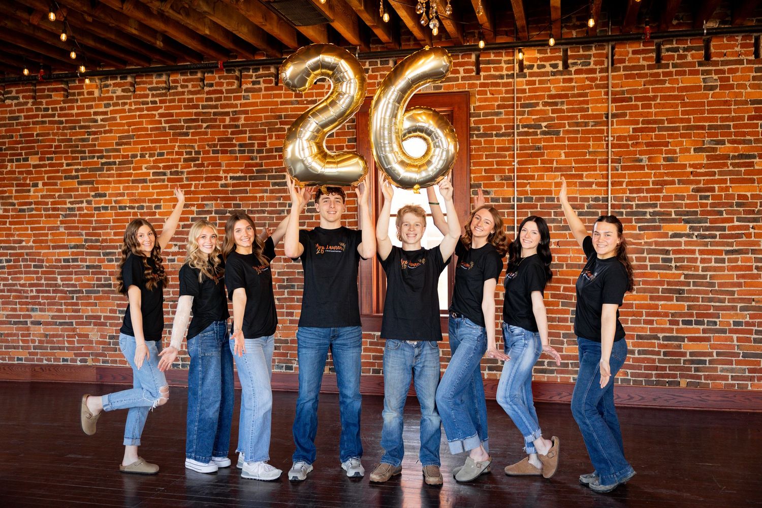 A creative panoramic photo sequence showing a group in blue jeans and dark tops walking against a brick wall.