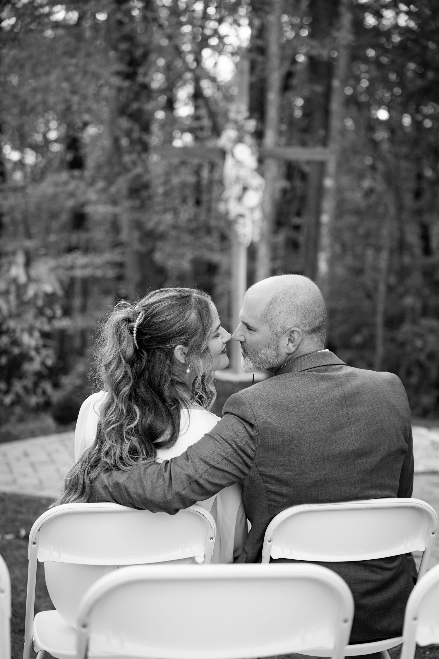 A romantic black and white photo of a couple sharing a tender moment while sitting together at the Haven at Cedar Grove.