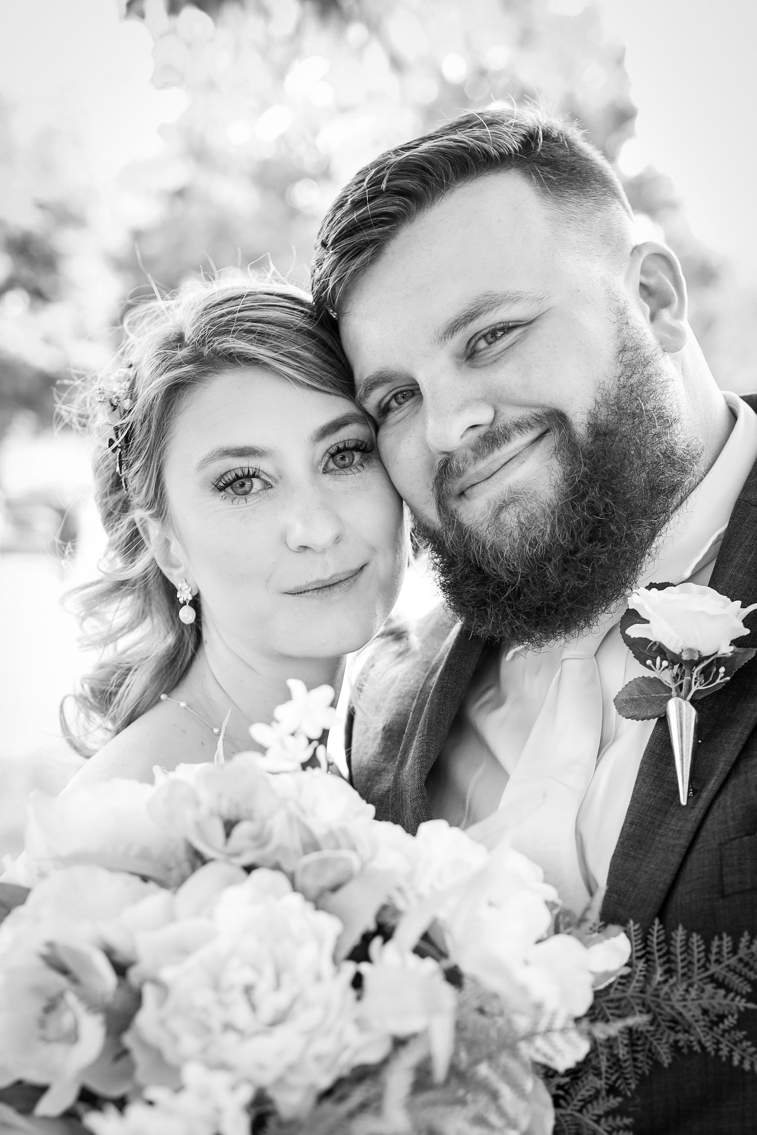 Black and white romantic wedding photos showing tender moments between newlyweds with white flowers.