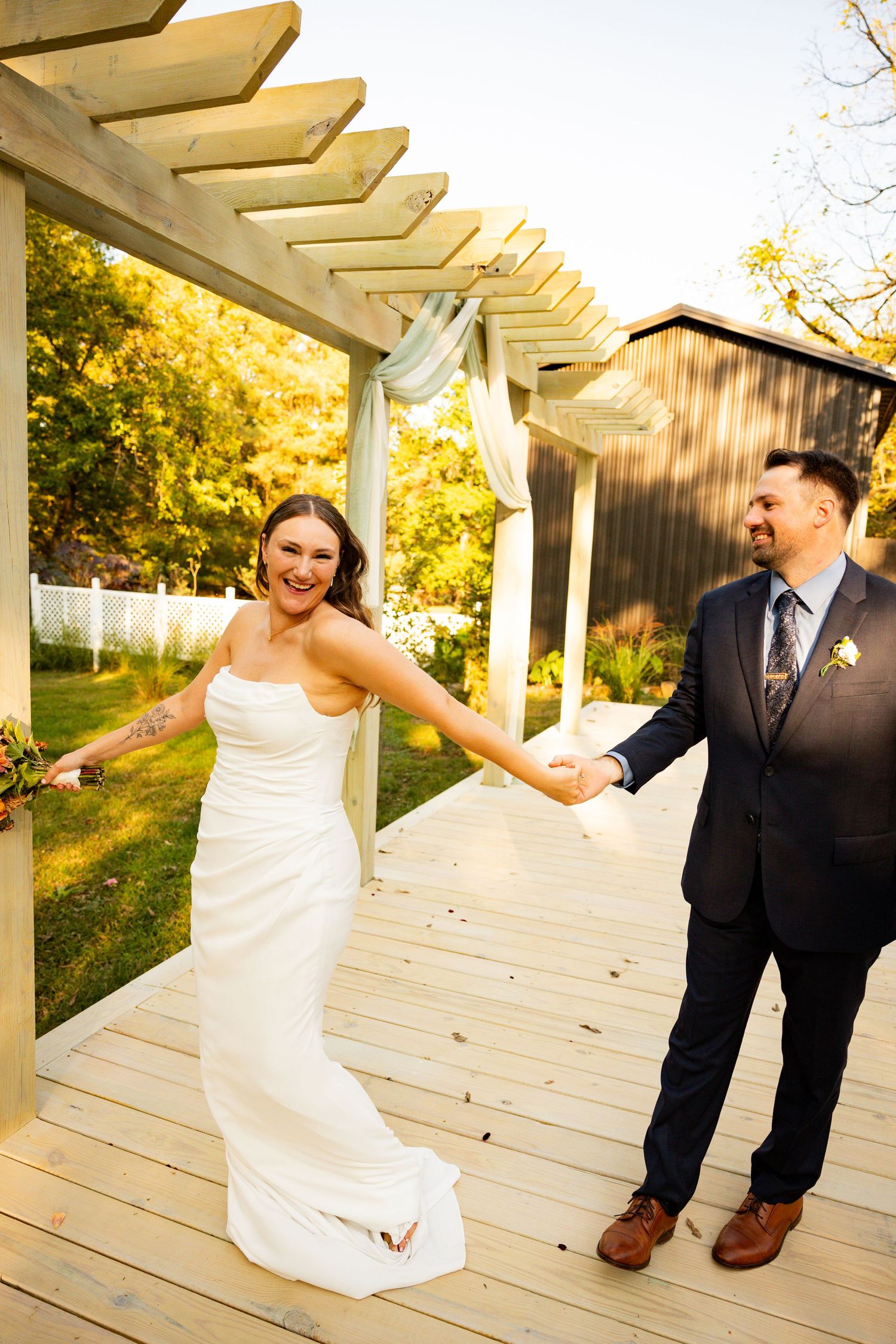 A couple shares a playful moment under a white pergola during their wedding photoshoot at sunset at The Henry Manor.