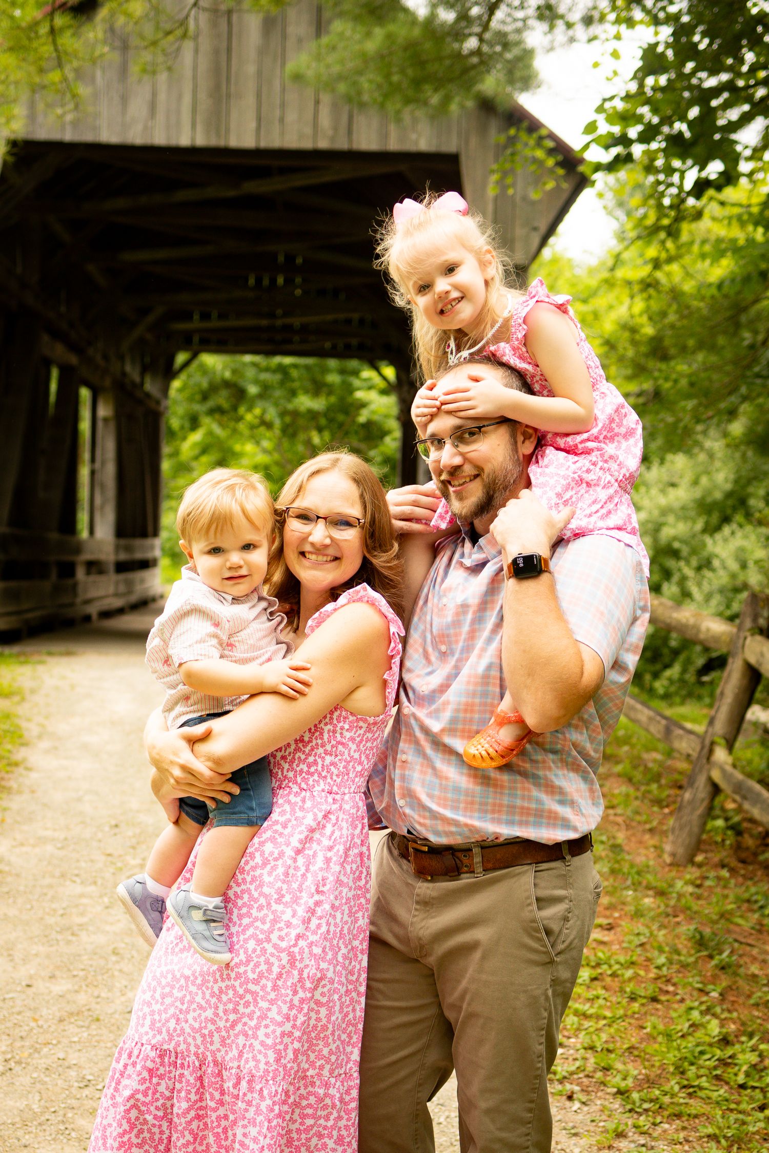 A family shares playful moments together on a wooded path during an outdoor photo session.