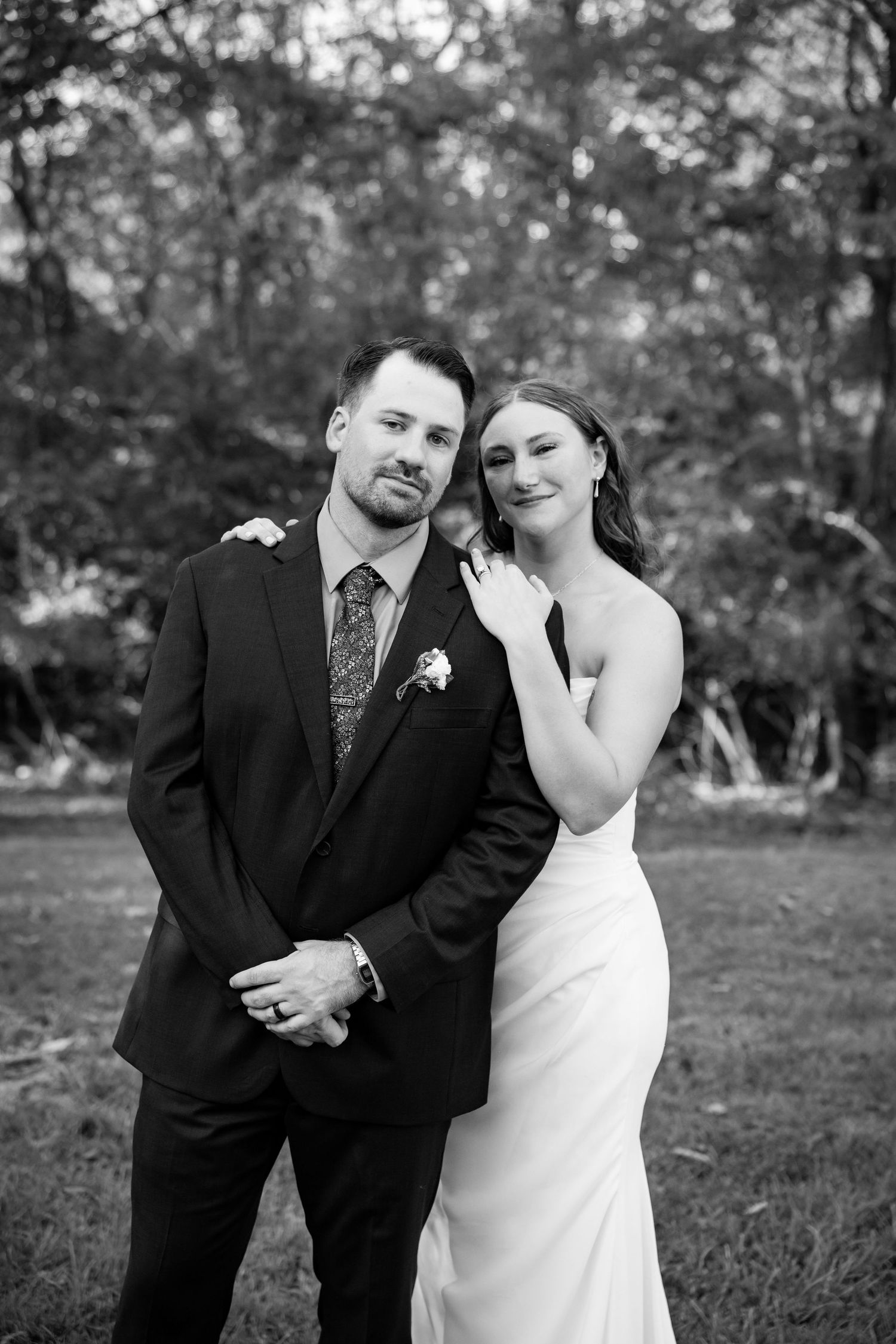 Black and white wedding photos showing couple in formal attire embracing outdoors in a natural setting.